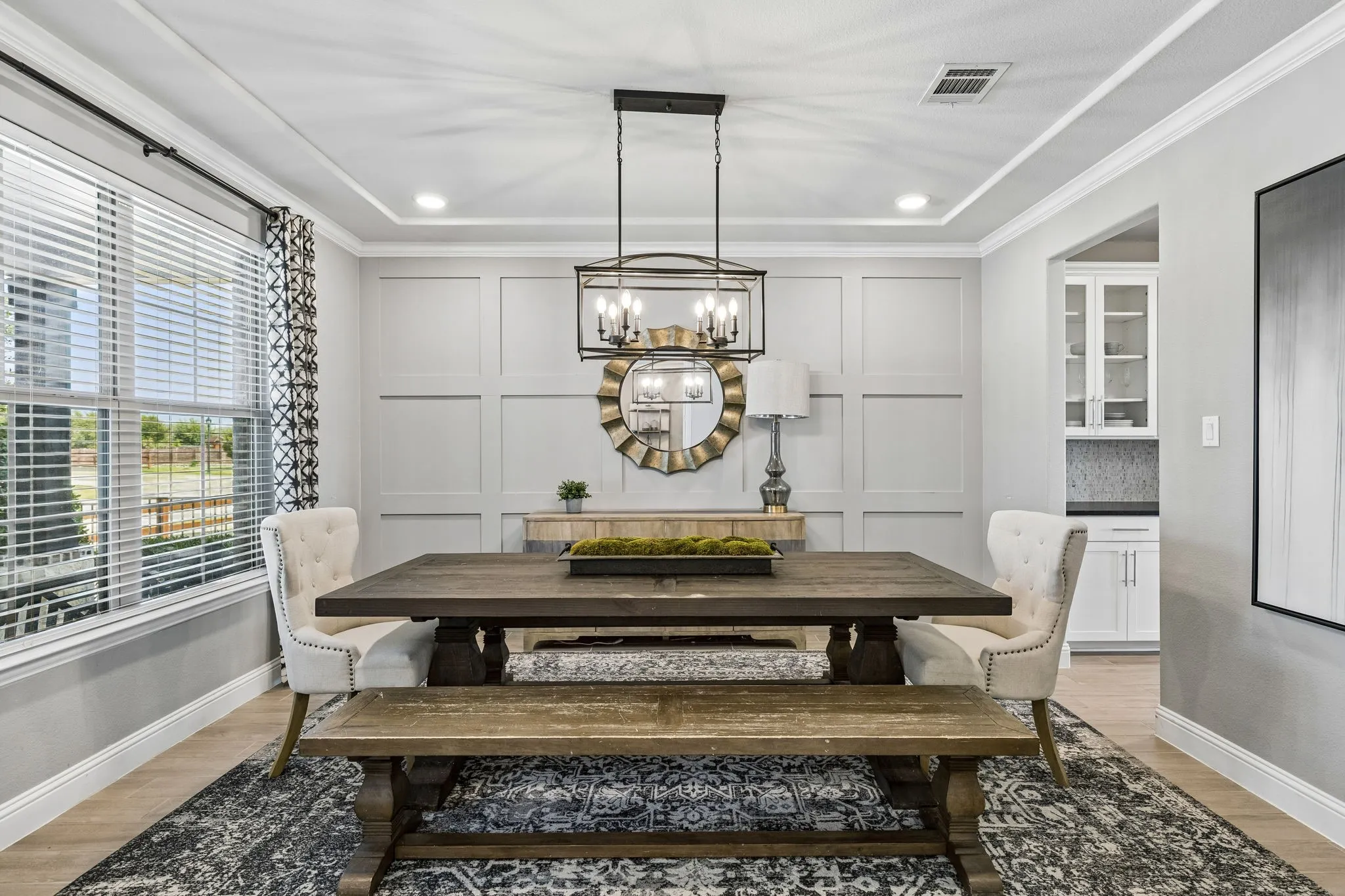 Refined formal dining room offers timeless architectural paneling, an elegant chandelier, designer-inspired finishes, and abundant natural light through expansive windows.