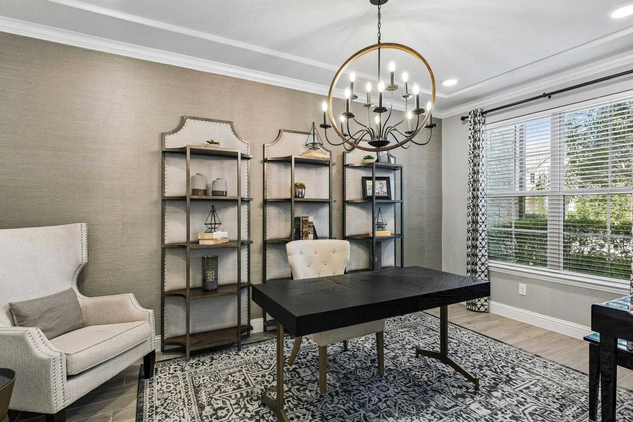 Elegant private study features sophisticated textured walls, oversized windows, and a statement chandelier creating a polished workspace.