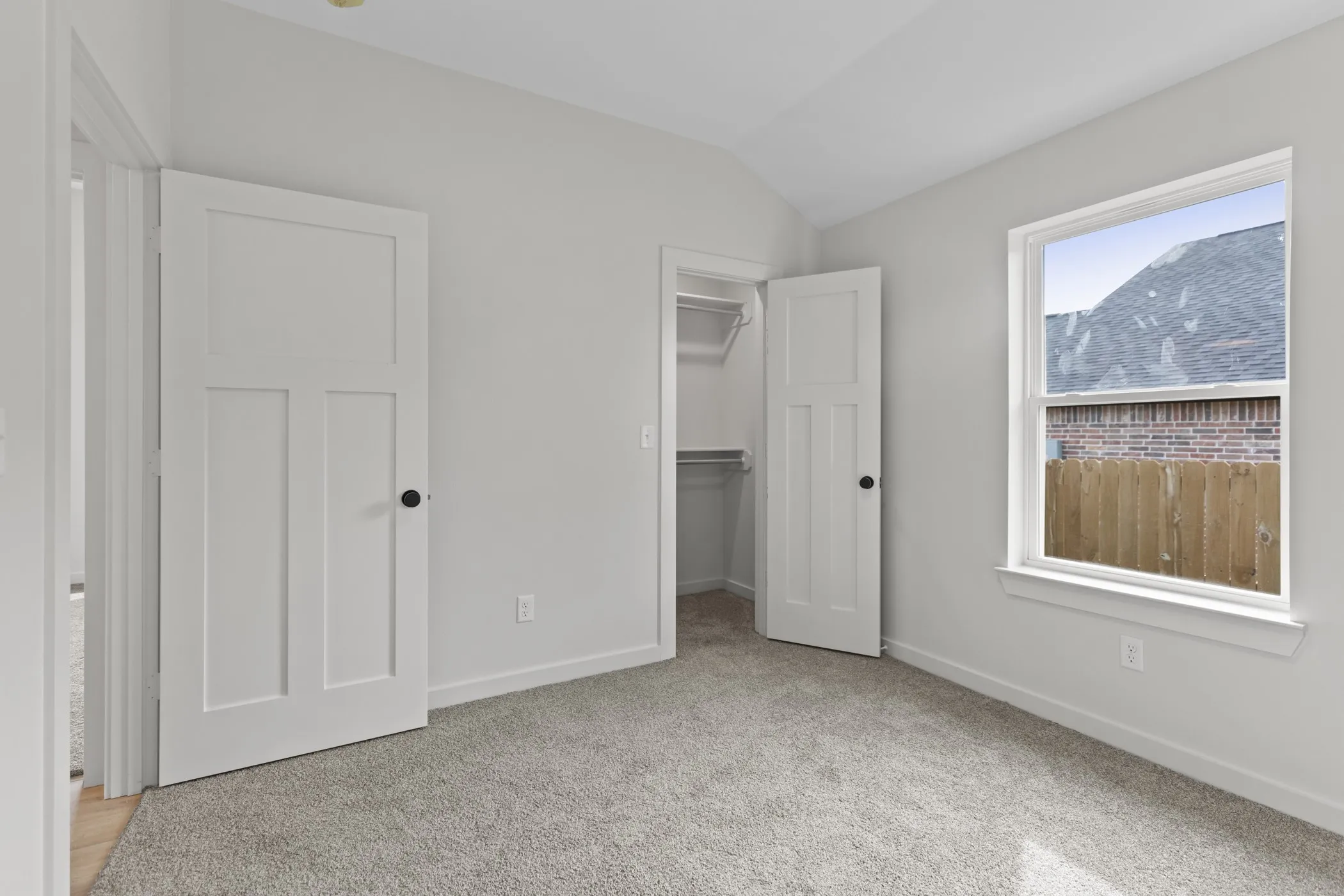 Carpeted room with white walls, a single window, and a built-in closet with shelving and hanging rod