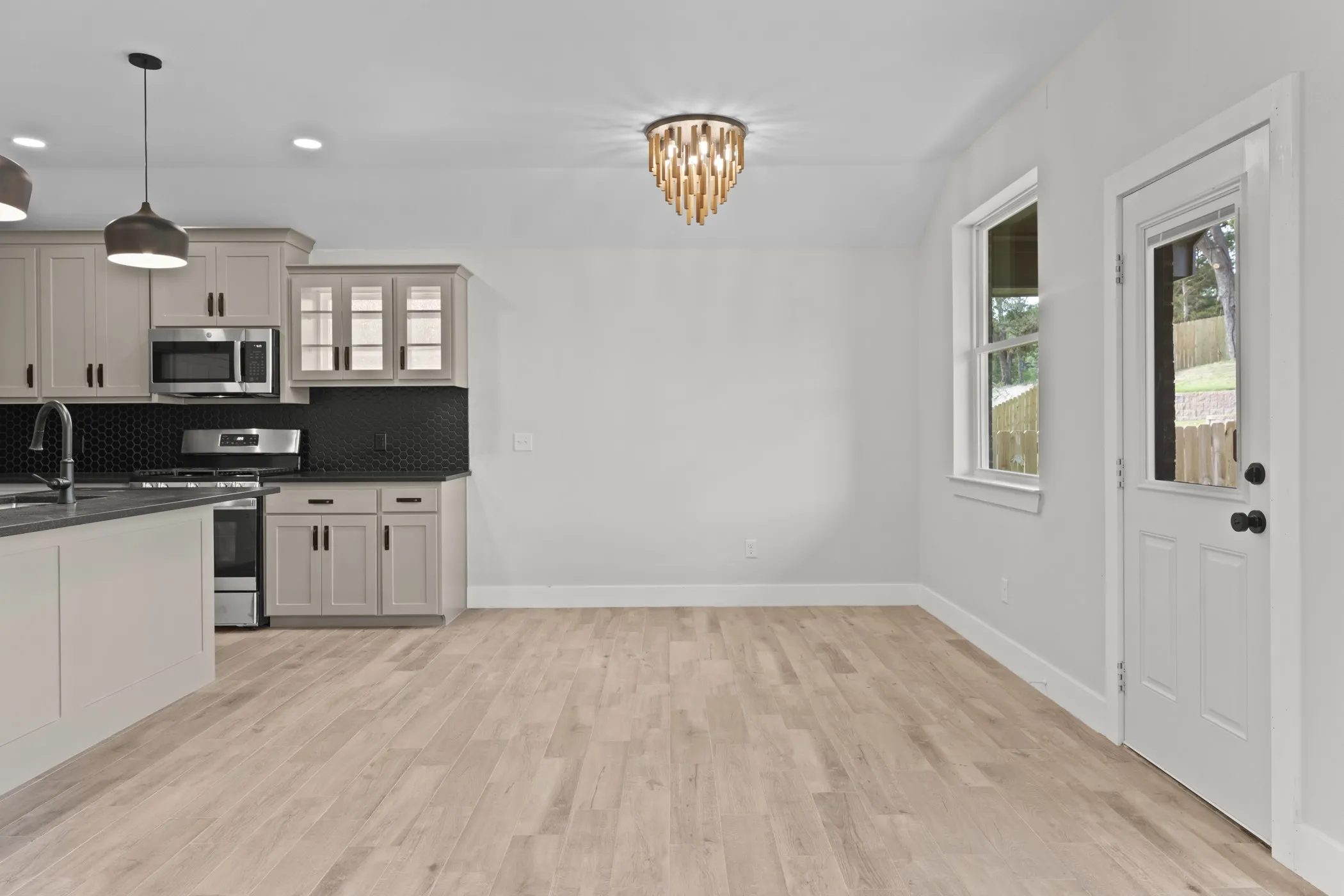 Kitchen and dining area featuring light-toned wood-finish flooring, recessed lighting, and a decorative ceiling fixture