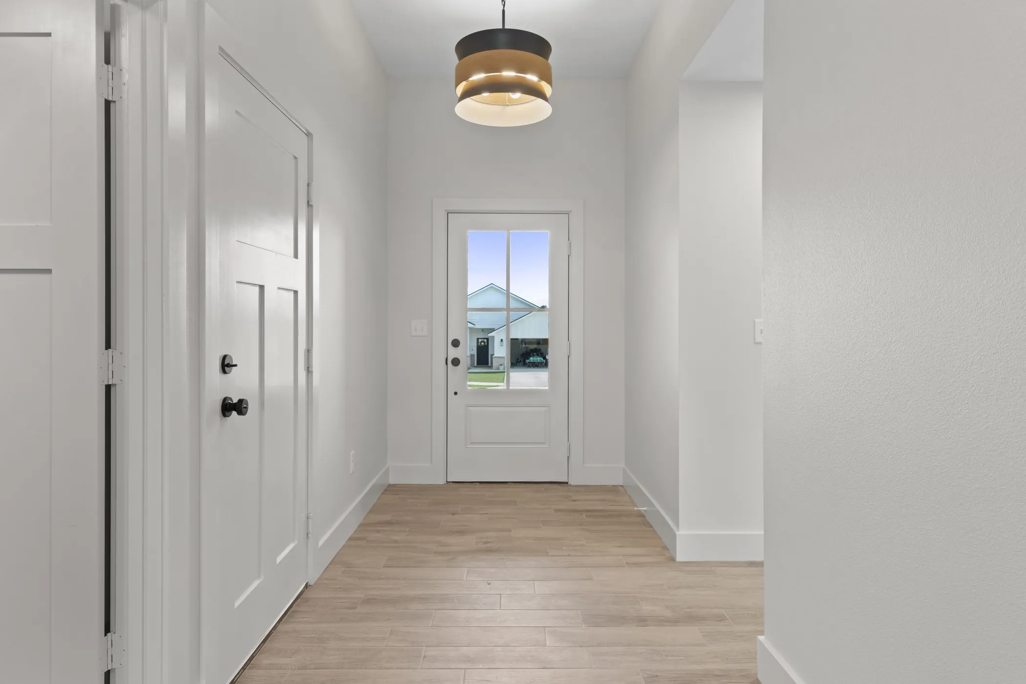 Light wood-finish flooring, white paneled doors, and a decorative semi-flush mount light fixture