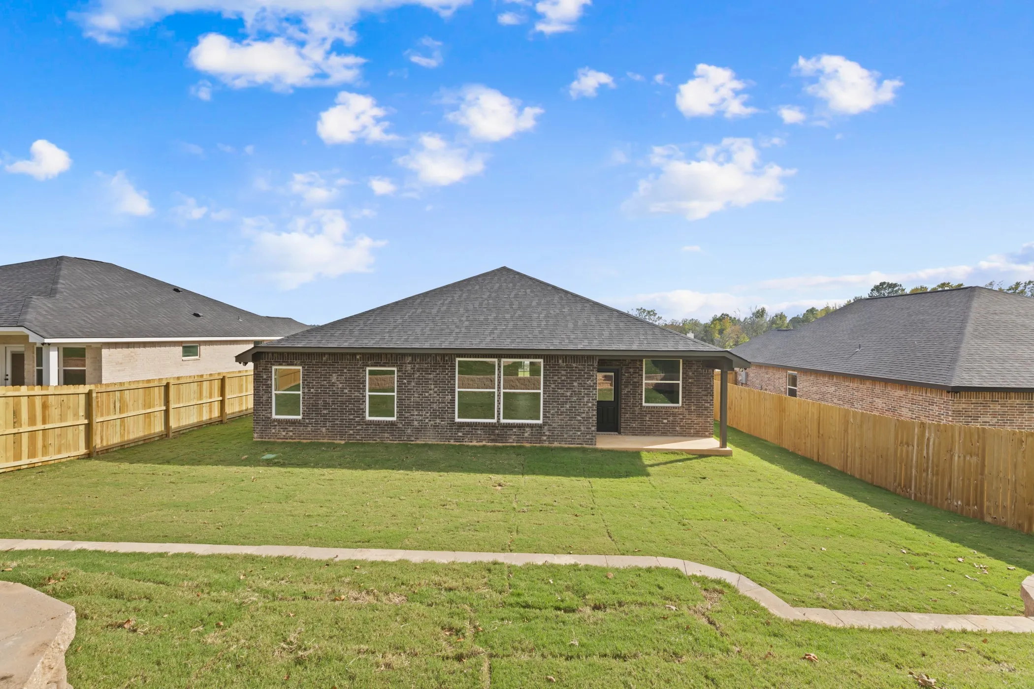 Expansive backyard featuring a manicured lawn, full privacy fencing, and a covered patio area