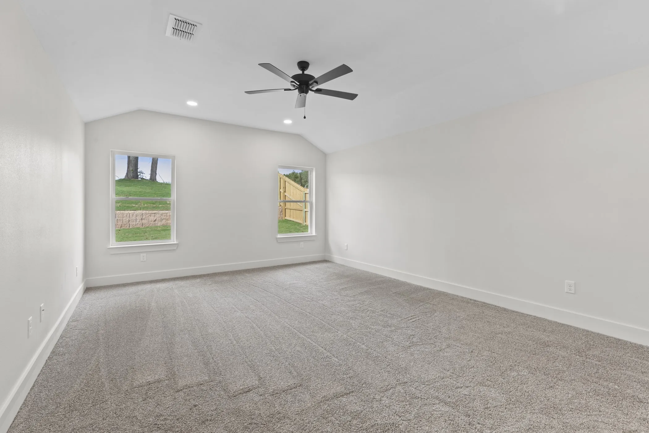Vaulted ceiling with recessed lighting and a ceiling fan, plush carpet, and two windows