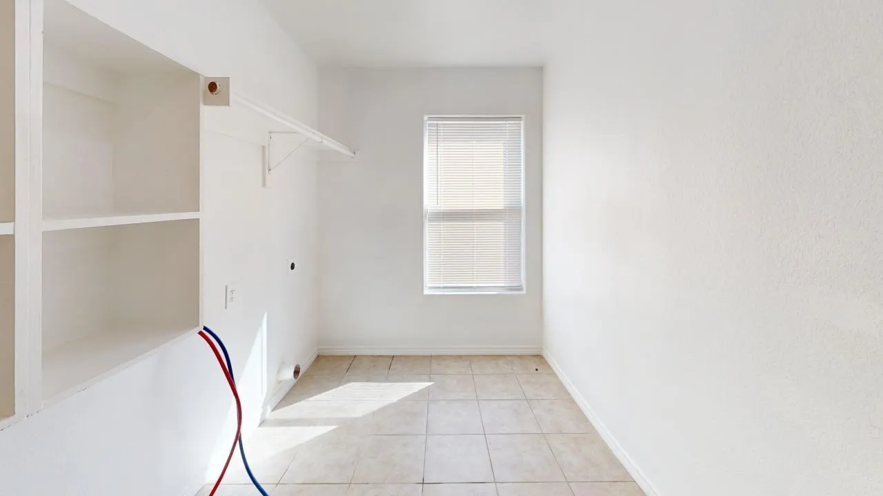 Built-in shelving, a single window with blinds, and tile flooring