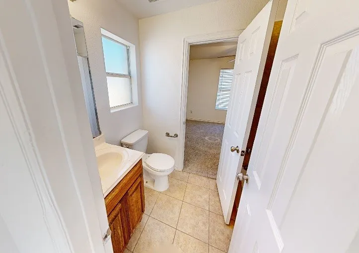 Bathroom featuring a vanity with wood-finish cabinetry, a single sink, and a toilet