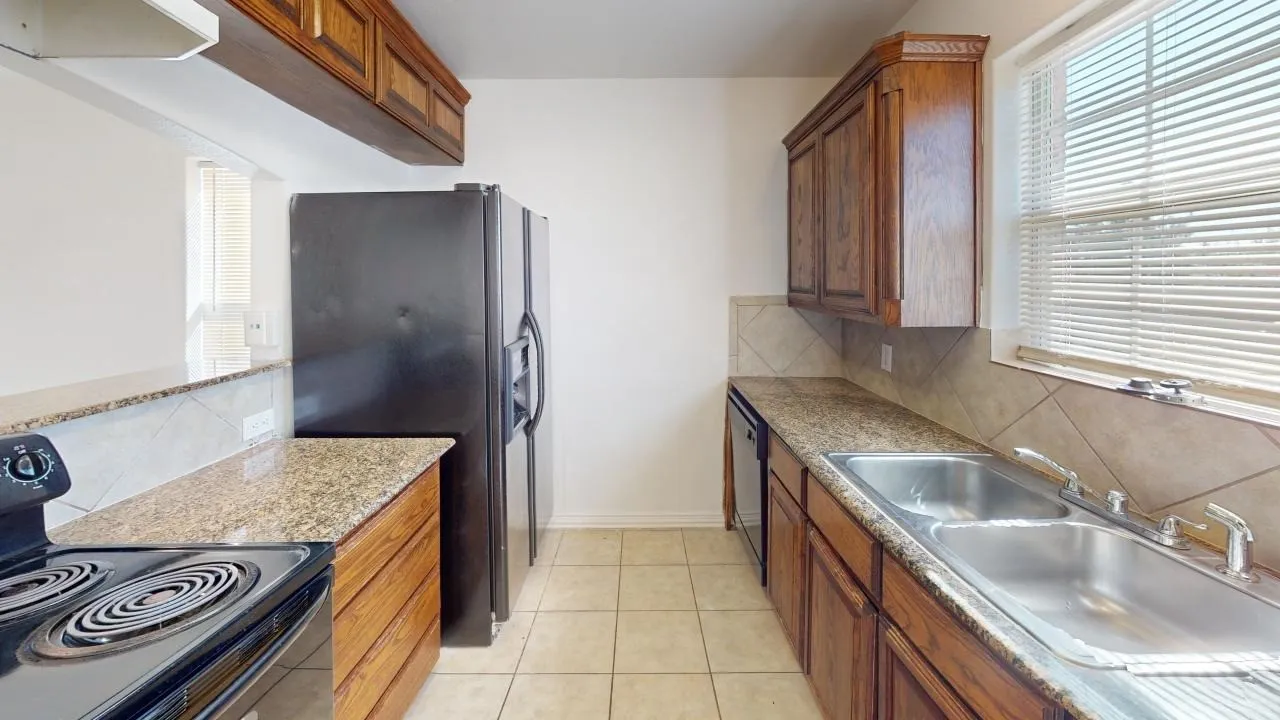 Kitchen featuring wood cabinetry, granite-finish countertops, and a tiled backsplash