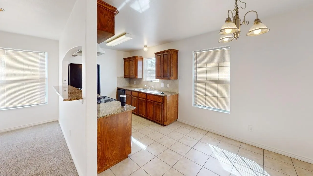 Kitchen with wood cabinetry, granite-style countertops, and tile flooring