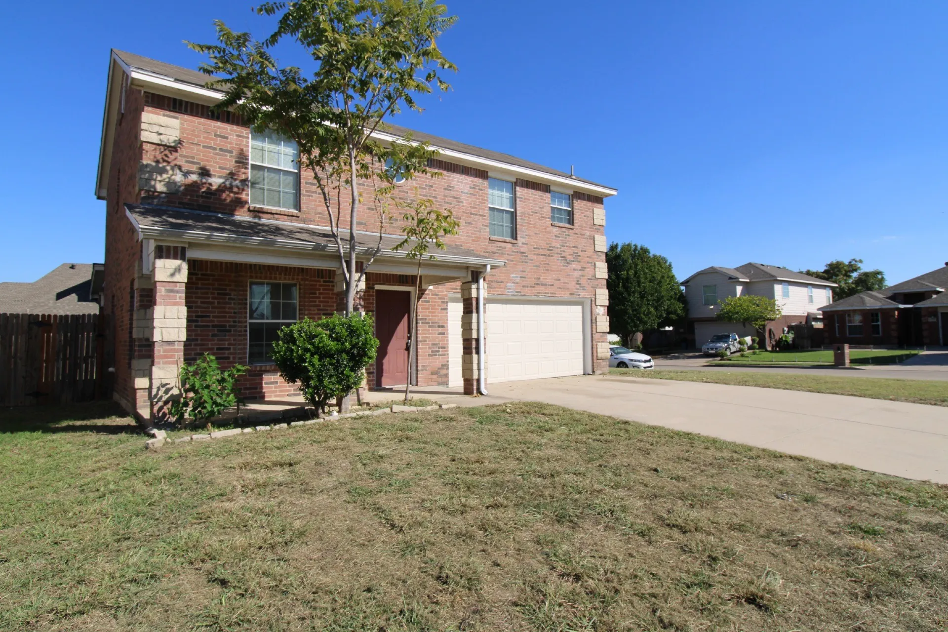 Brick exterior with stone accents, covered front porch, attached garage, and a concrete driveway