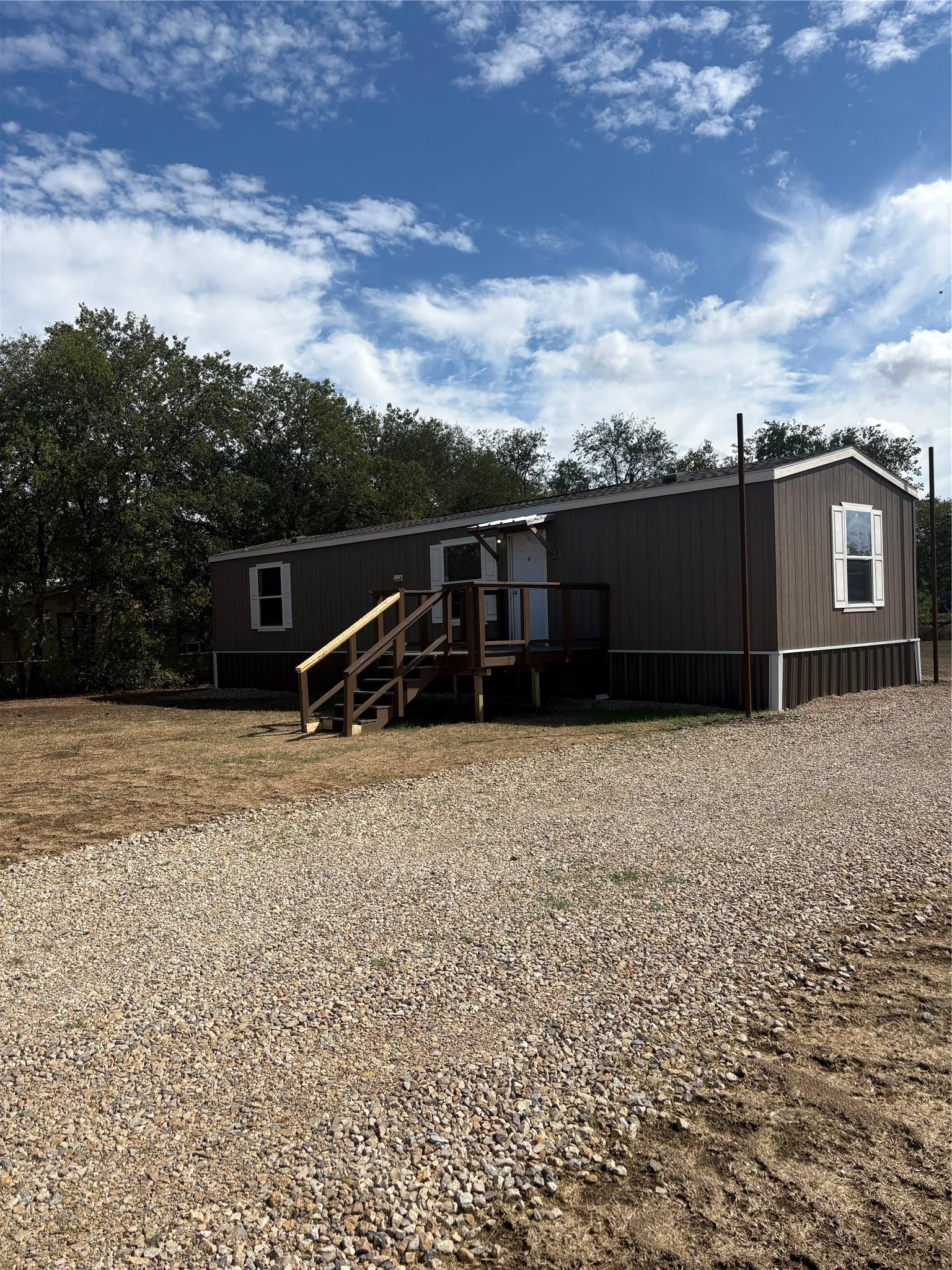 Brown siding exterior with white trim windows and a natural wood-finish front porch and stairs