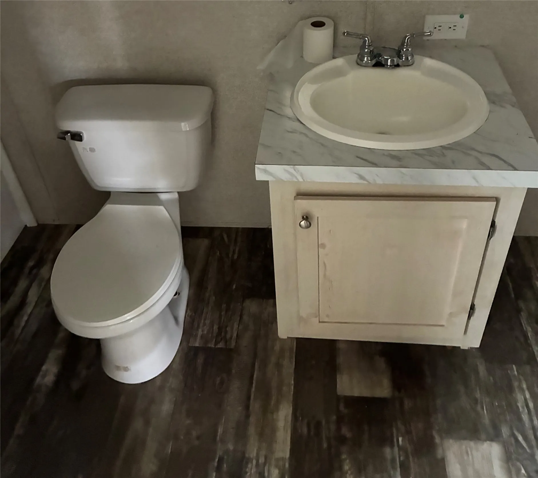 Bathroom featuring a white toilet, single vanity with a white basin and chrome faucet, light-toned cabinetry, and wood-finish flooring