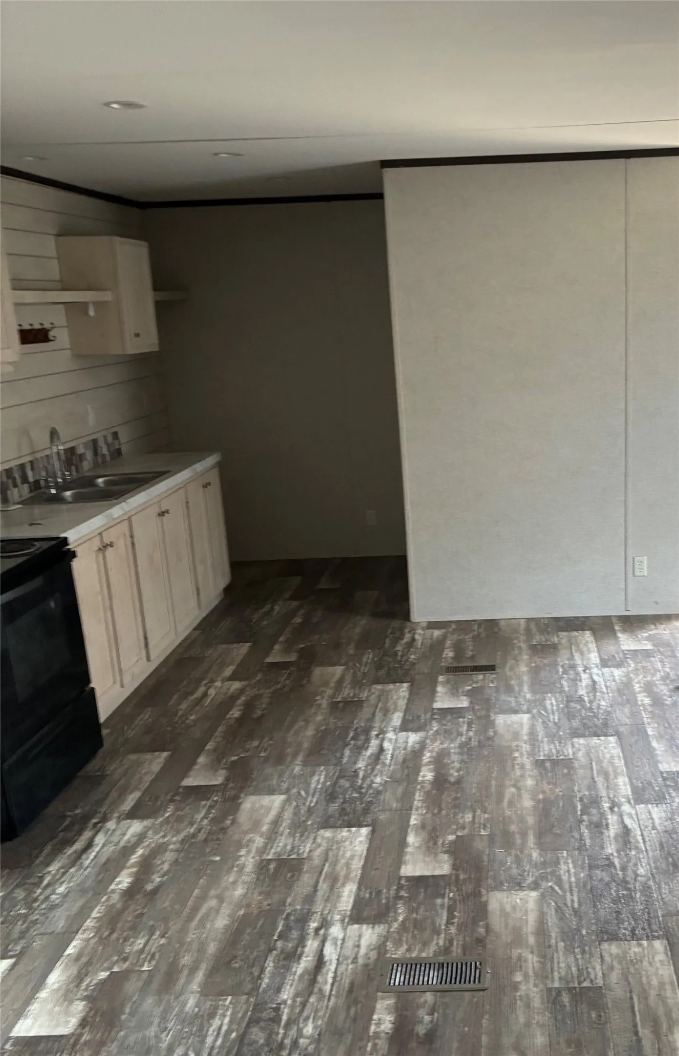 Modern kitchen featuring white cabinetry, wood-finish flooring with mixed-tone planks, and built-in black appliances
