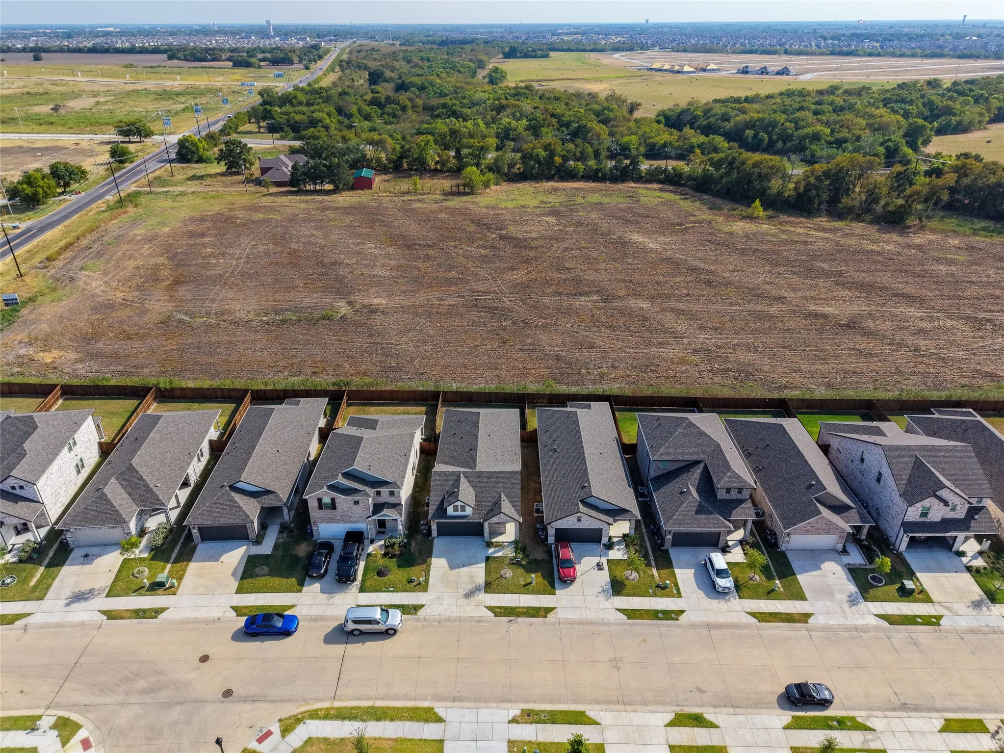 Row of residential properties with varied architectural styles, asphalt shingle roofs, attached garages, and concrete driveways