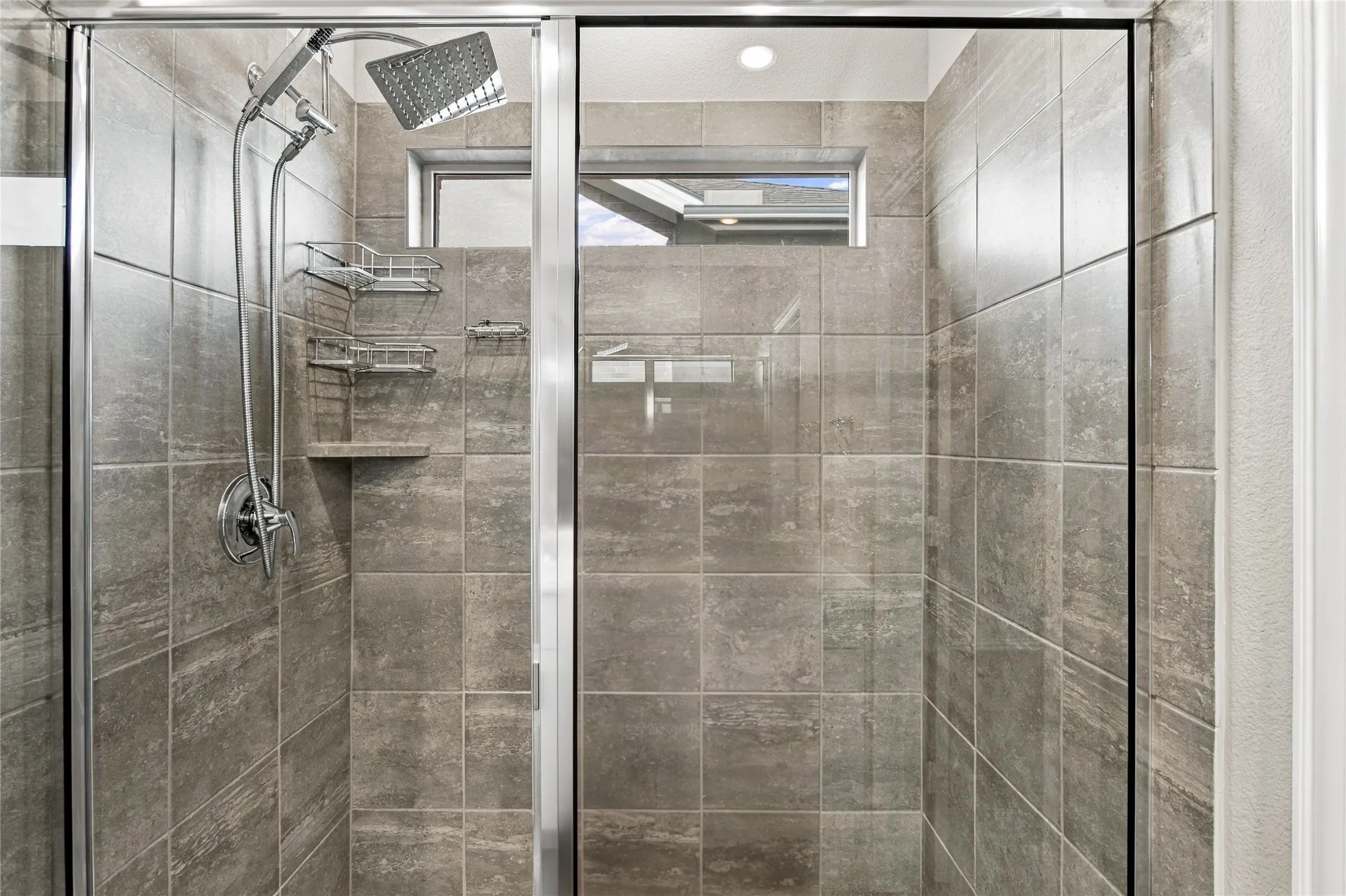 Enclosed shower with full-height tile surround, built-in tile shelf, and multiple shower heads