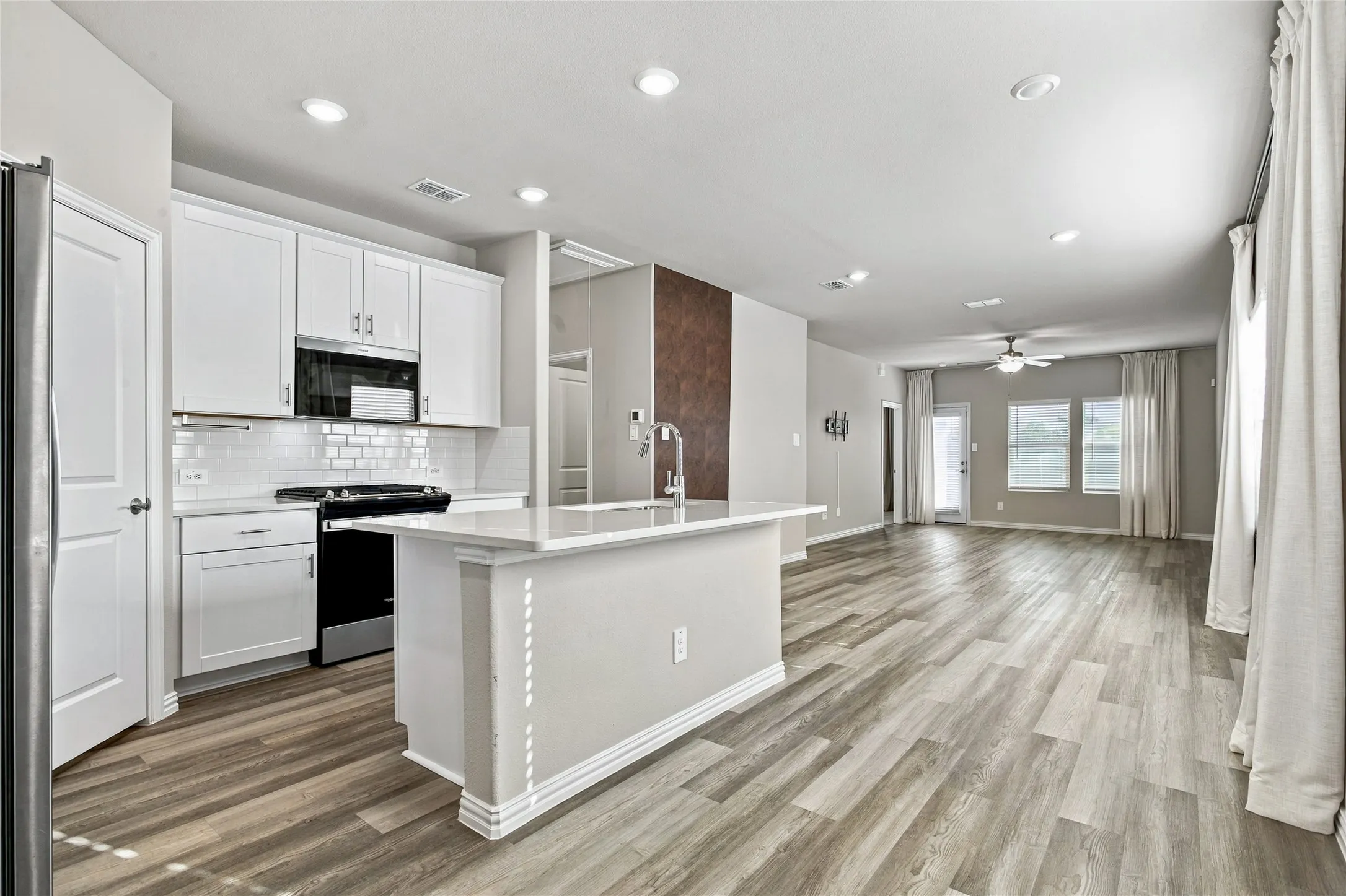Kitchen featuring white shaker cabinetry, subway tile backsplash, and a central island