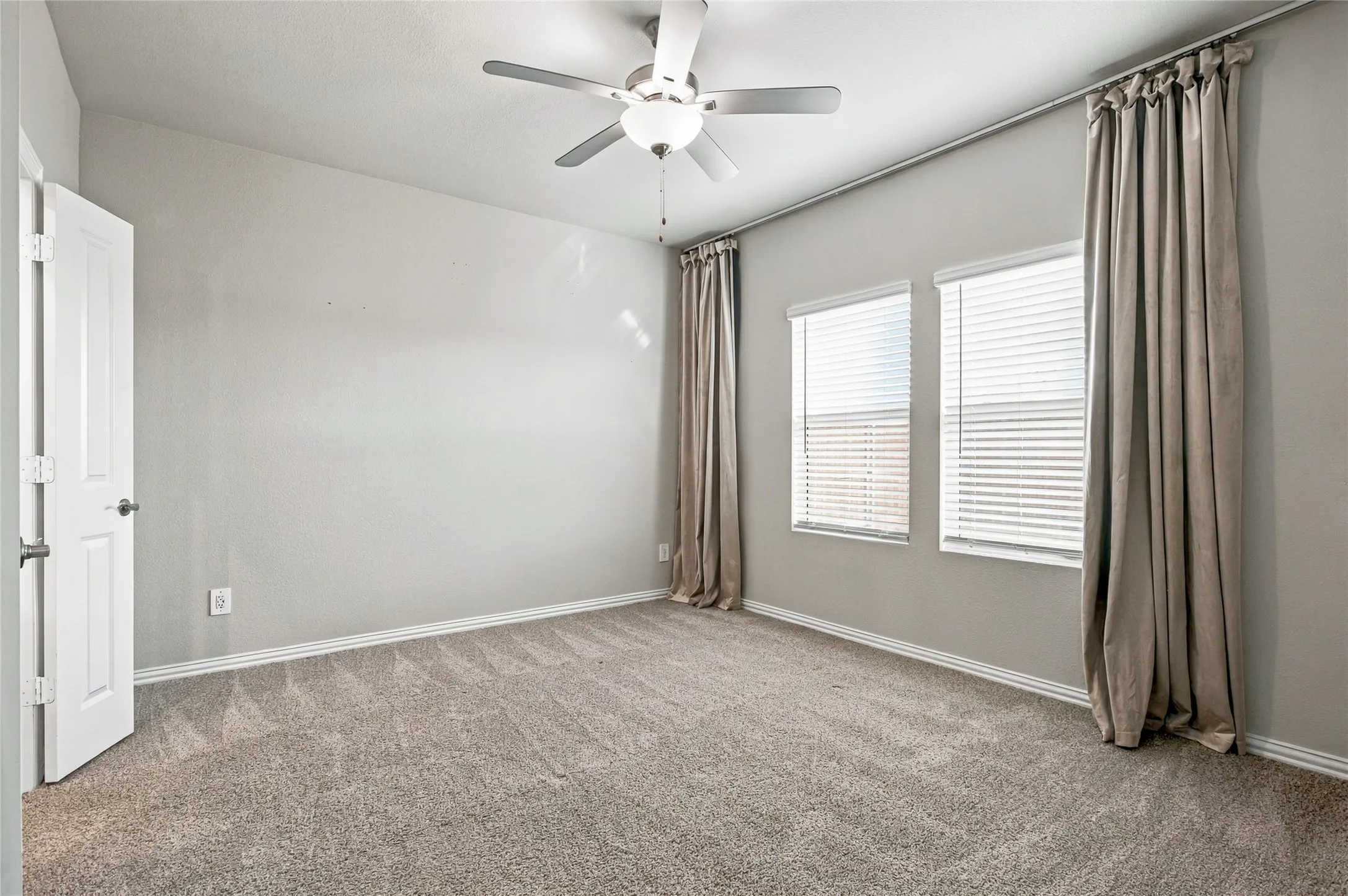 Carpeted room with neutral walls, white trim, and a ceiling fan