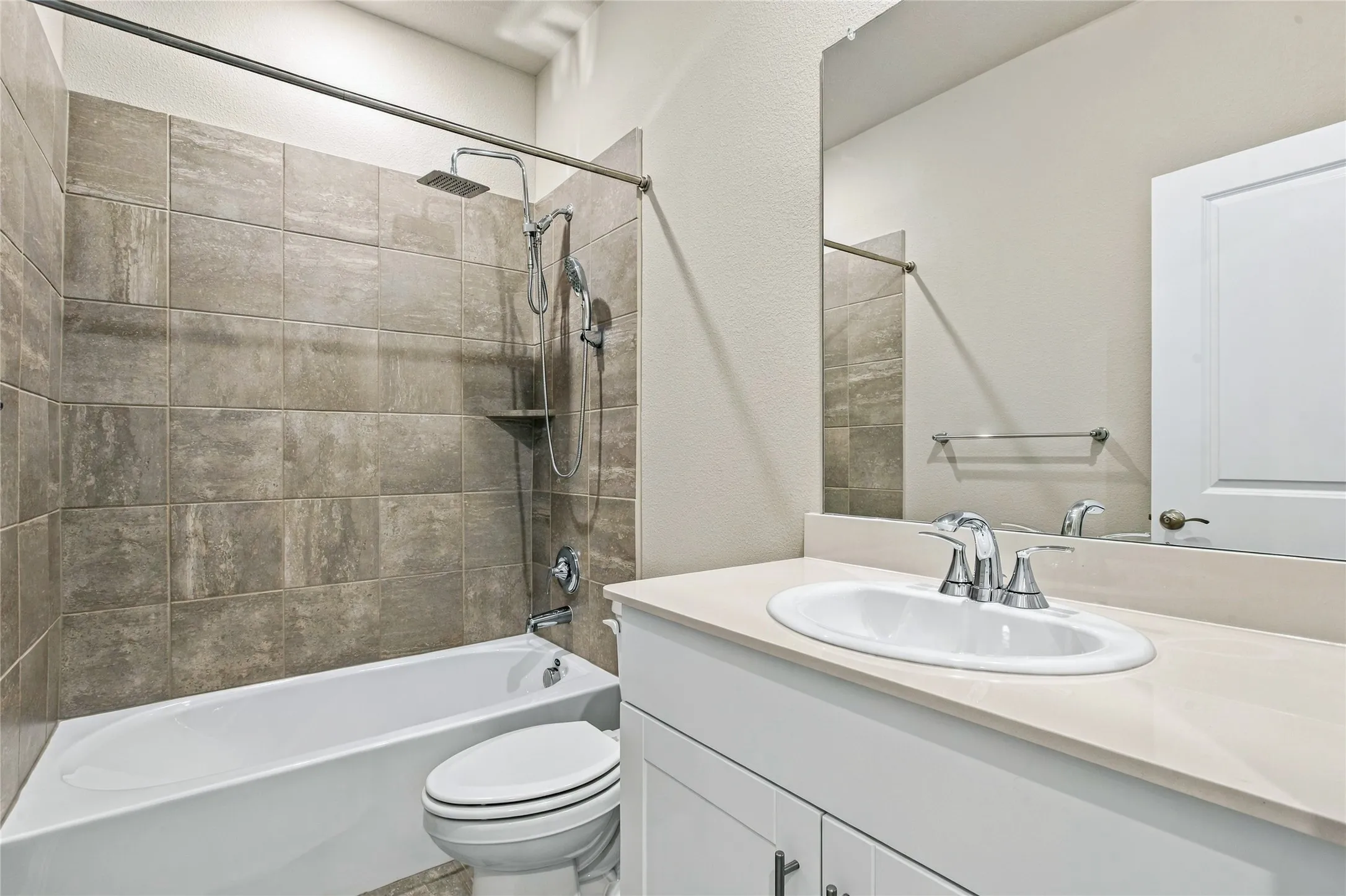 Modern bathroom featuring a ceramic vessel sink with chrome faucet and widespread handles, white vanity cabinetry with ample storage, frameless glass shower enclosure, subway tile surround in neutral tones, and an integrated bathtub-shower combination with chrome fixtures