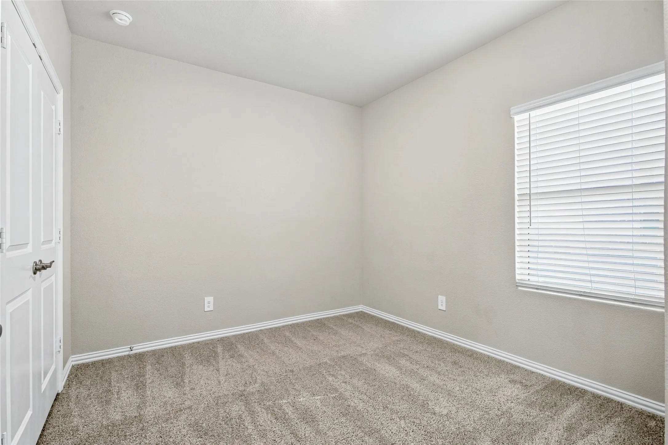Recessed ceiling light fixture, neutral wall paint, carpeted flooring, white trim, and a window with blinds
