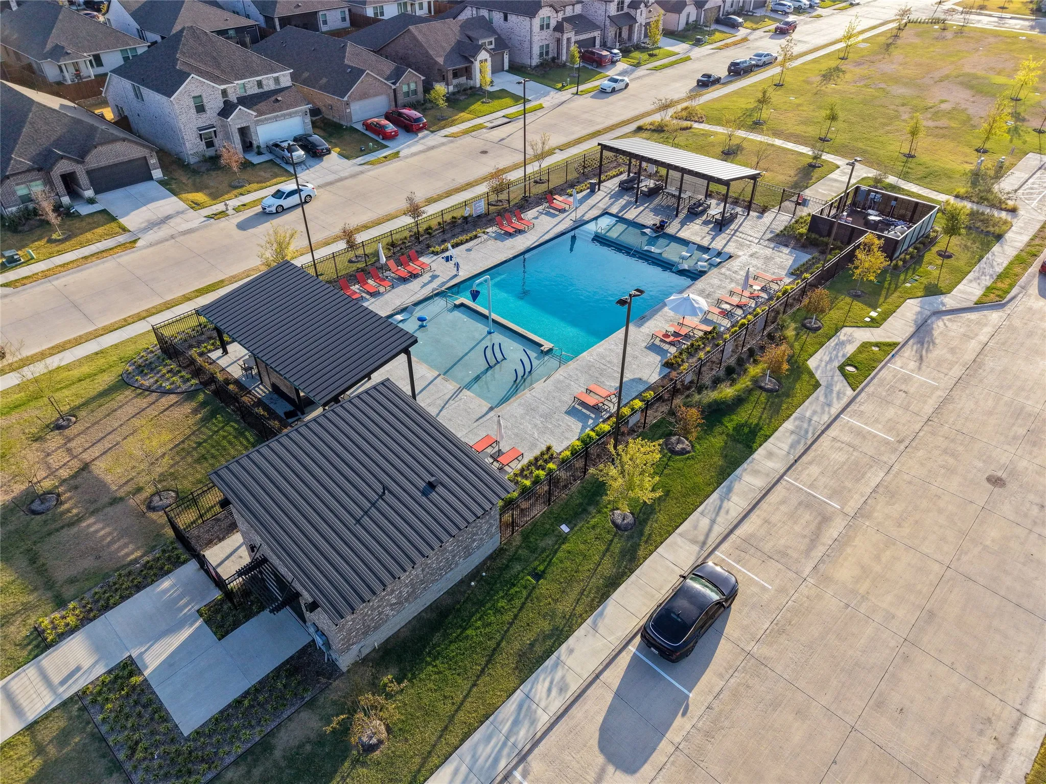 Community swimming pool with surrounding concrete decking, two covered cabanas, and integrated lounge seating
