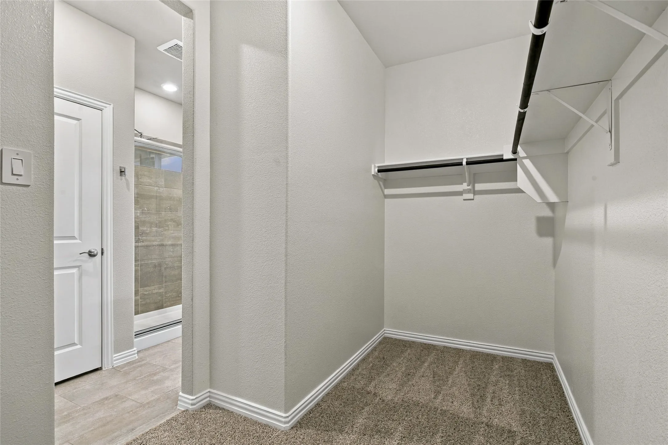 Carpeted closet space with multiple hanging rods and shelving