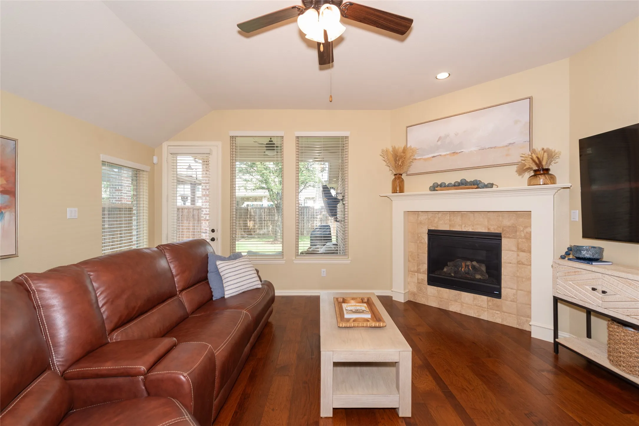 Living area featuring wood-finish flooring, vaulted ceiling, and a ceiling fan