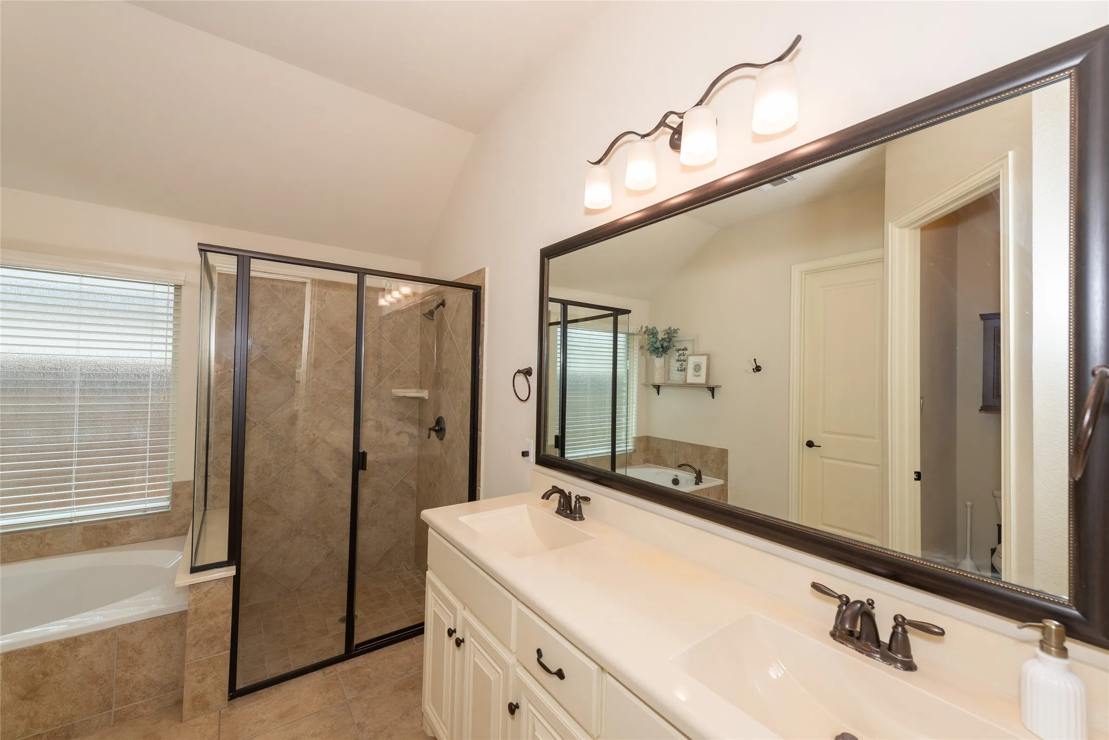 Dual vanity with undermount sinks, bronze fixtures, and a large framed mirror