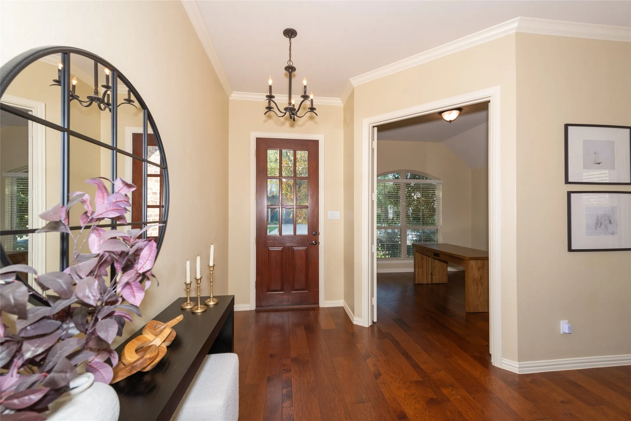 Hardwood flooring, crown molding, a paneled entry door with glass inserts, and a chandelier lighting fixture