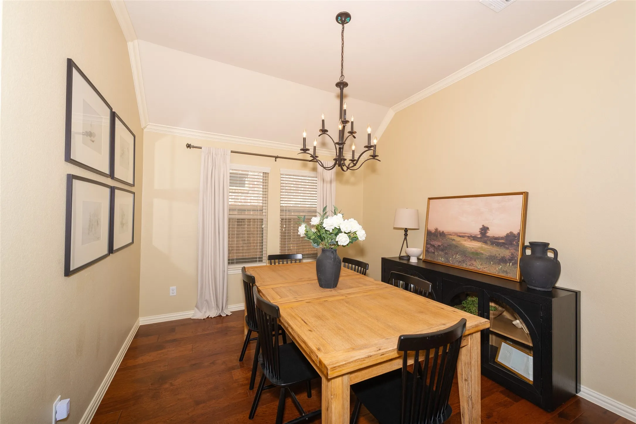 Vaulted ceiling, crown molding, wood-finish flooring, and a multi-pane window with blinds