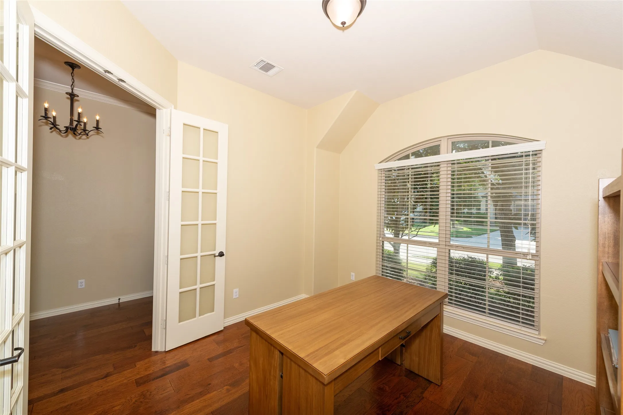 Wood-finish flooring throughout, French doors with glass panels, arched window, and recessed ceiling details