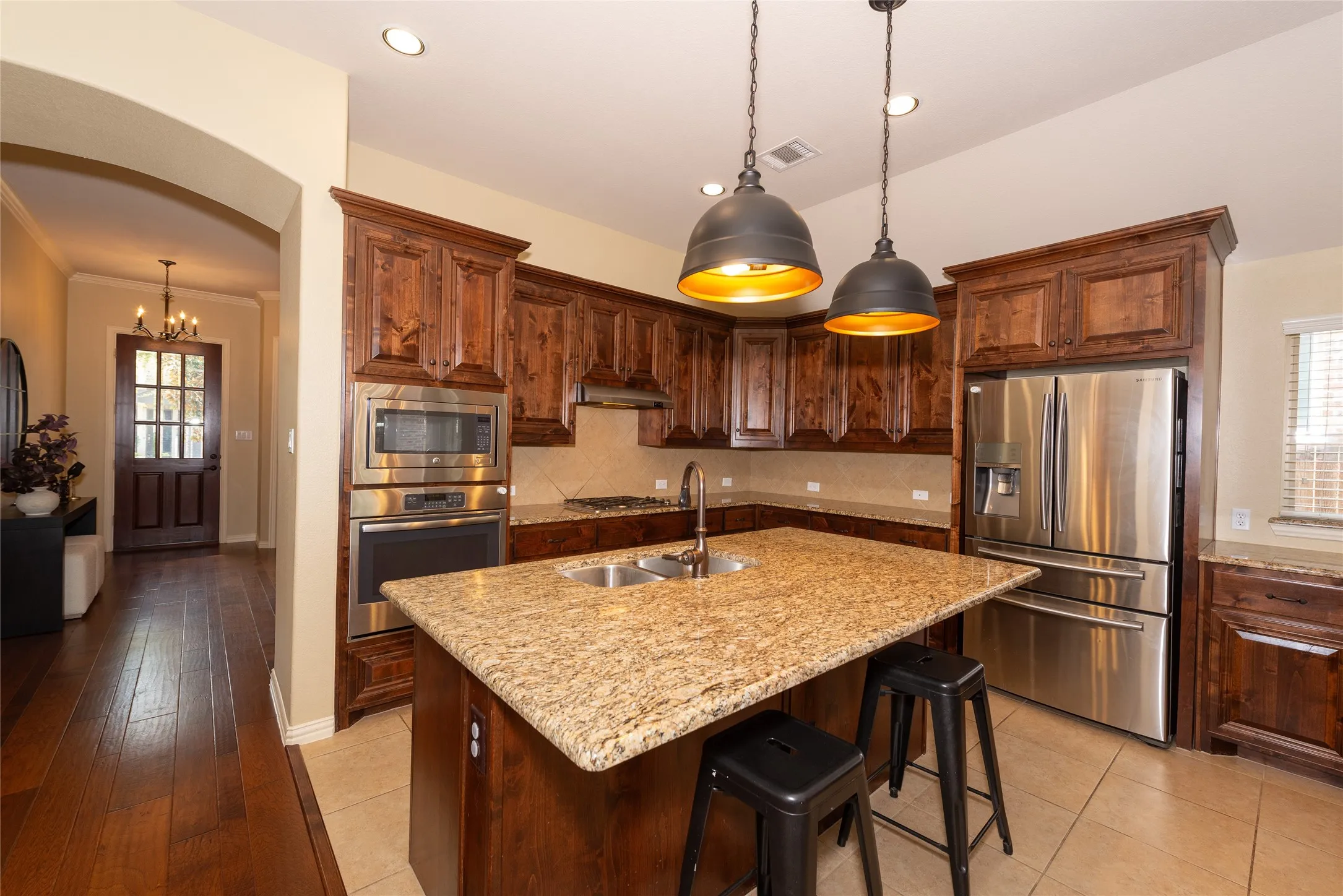 Kitchen featuring wood cabinetry, stainless steel appliances, an island with an undermount sink, and recessed lighting