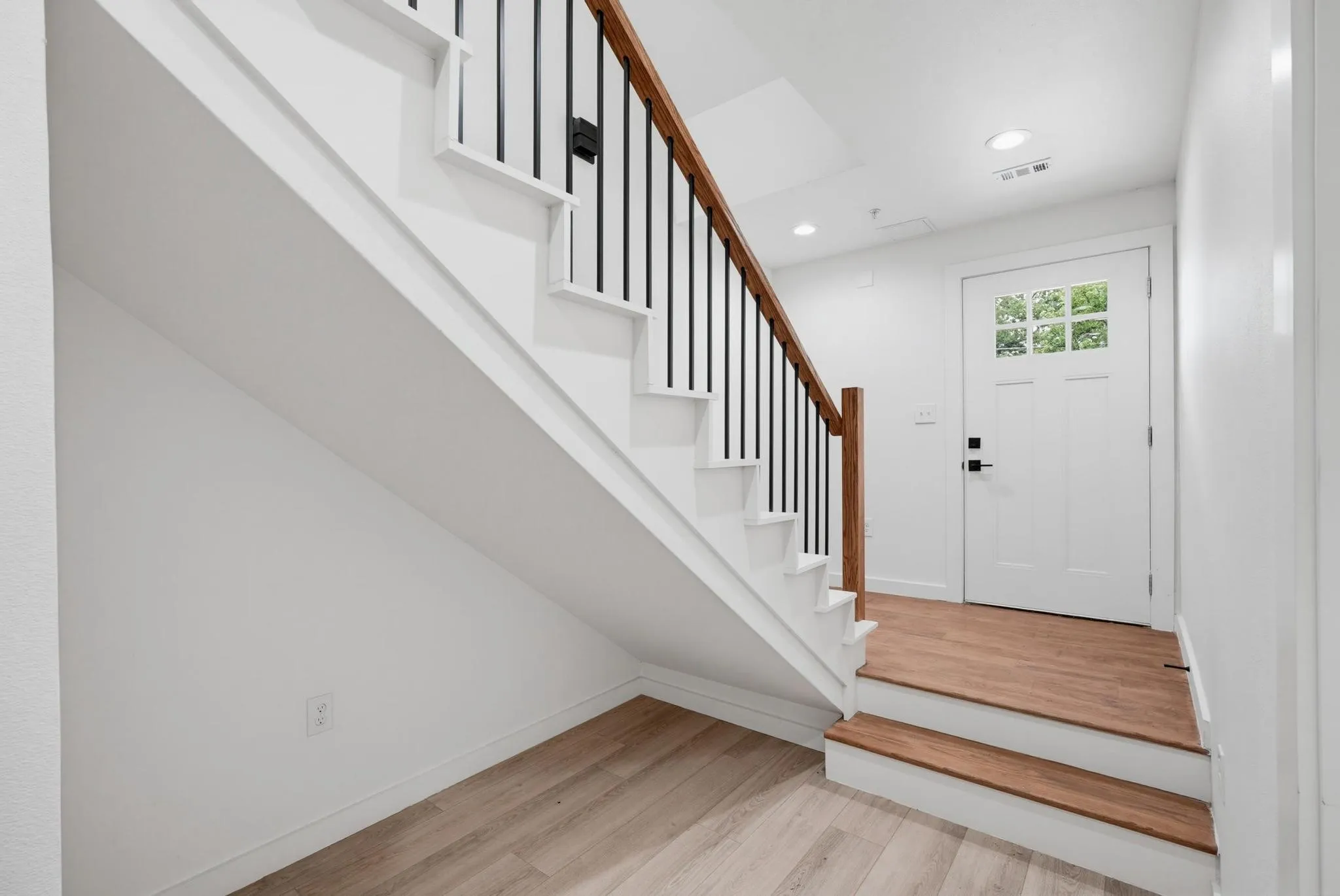 Entryway with wood-finish flooring, recessed lighting, and a white paneled door with glass inserts