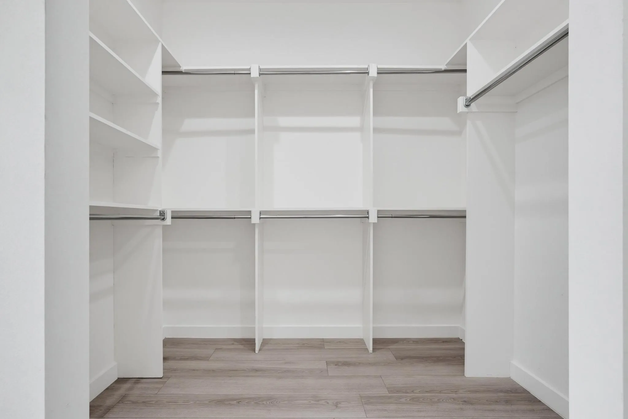 Built-in white storage system with multiple shelves and hanging rods