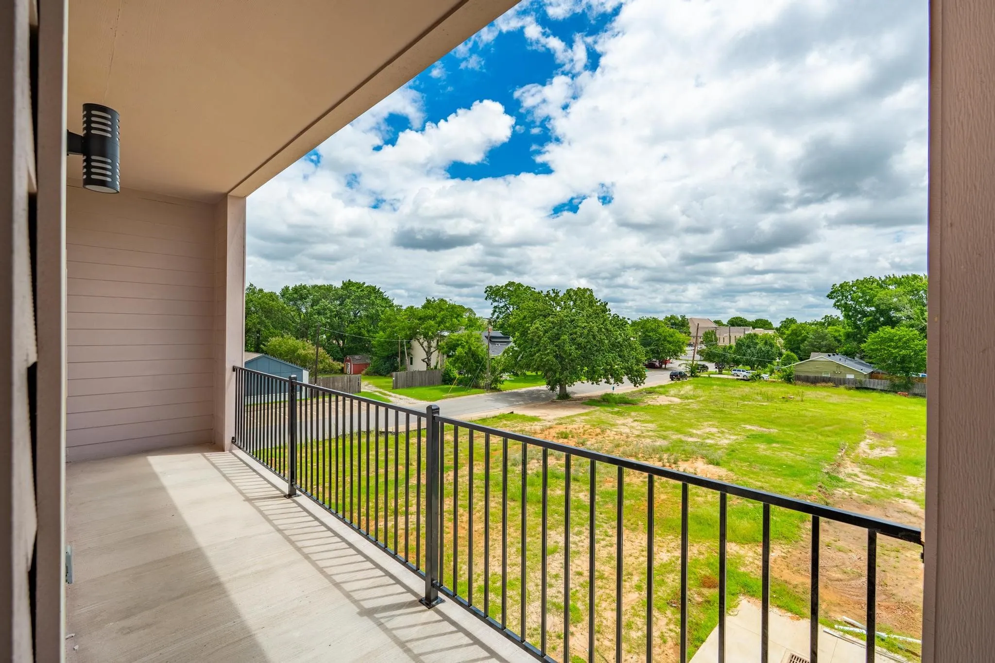 Private balcony with a black metal railing and a wall-mounted exterior light fixture
