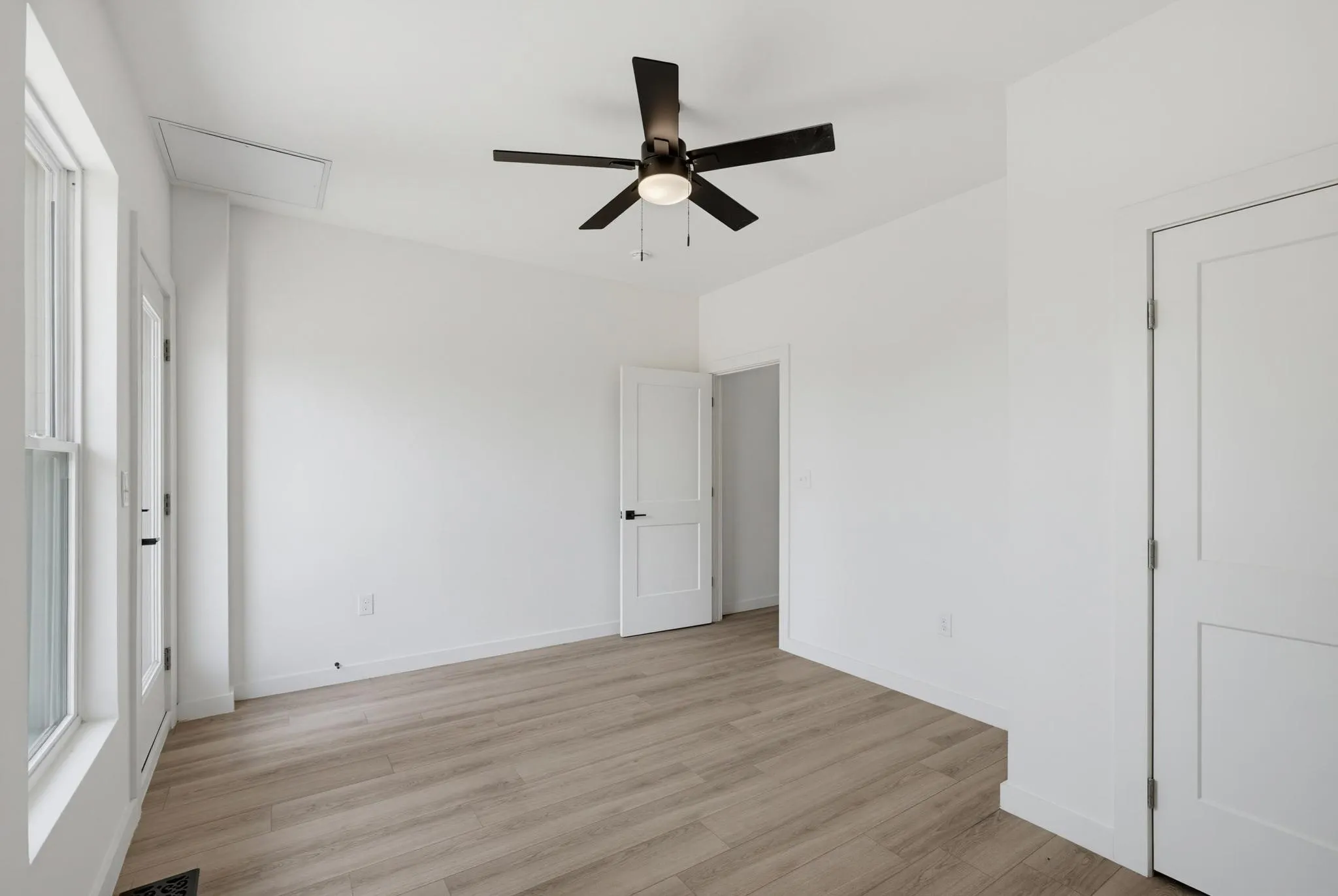 High ceilings featuring a dark-toned ceiling fan, light wood-finish flooring, and white walls