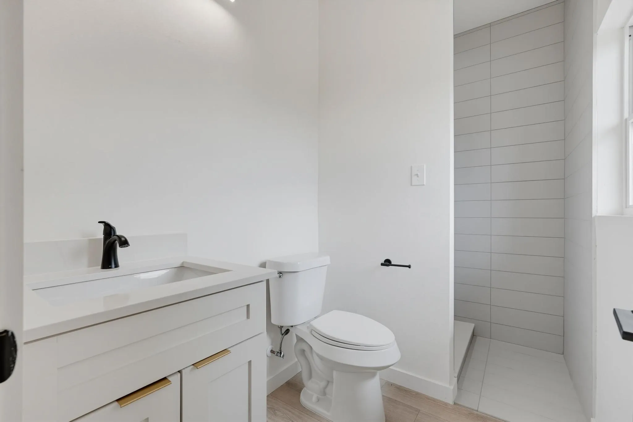 White vanity with gold-finish hardware, integrated sink, and black faucet