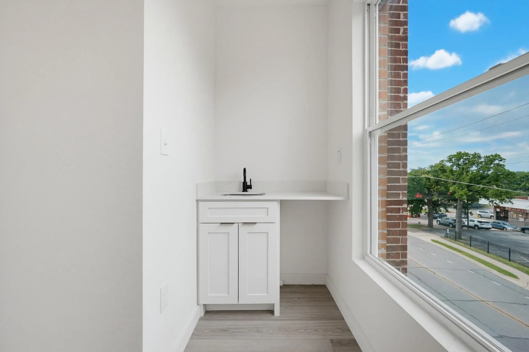 Built-in white cabinetry with a quartz countertop, integrated sink, and black faucet