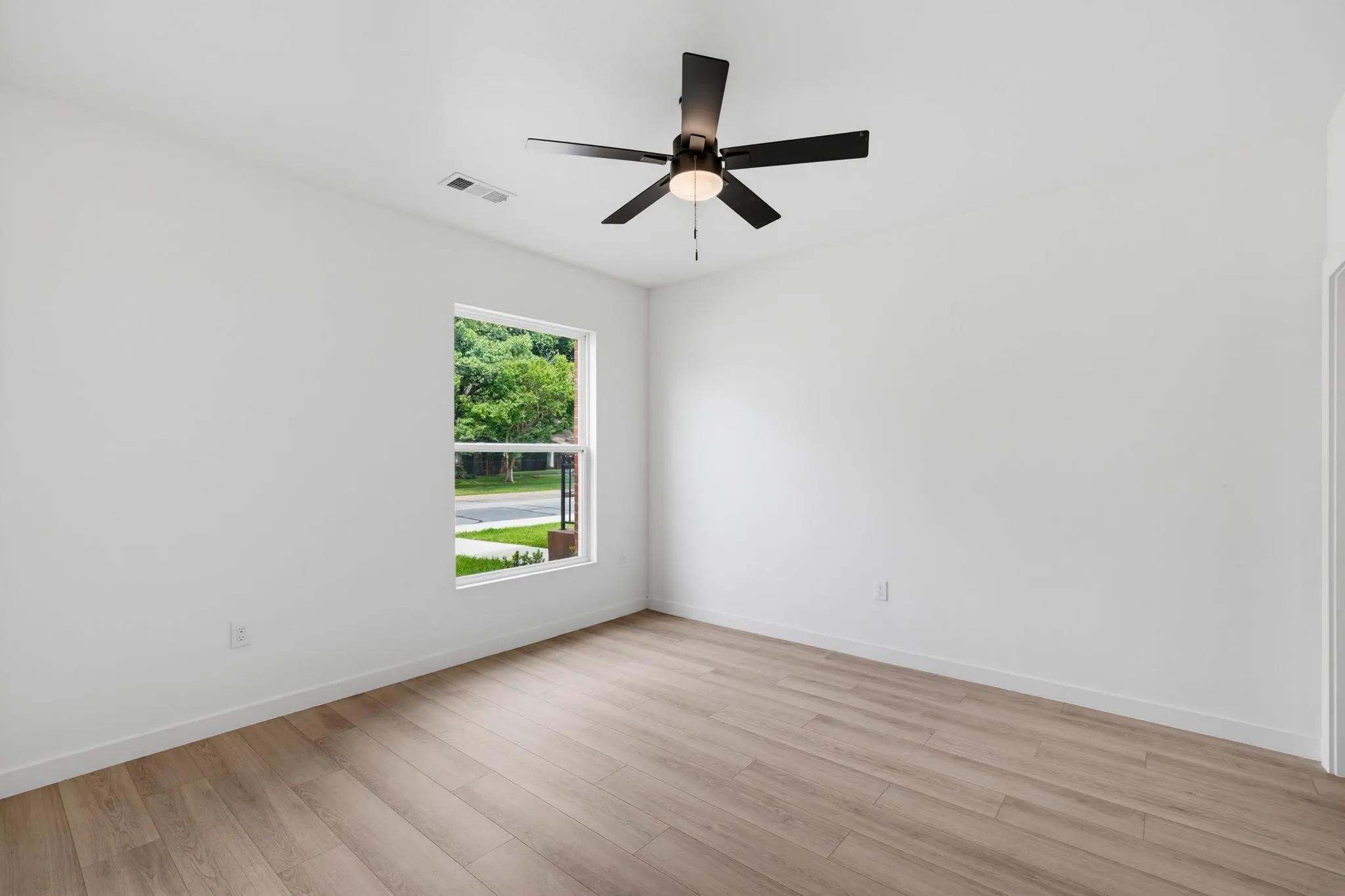 Wood-finish flooring, white walls, and a ceiling fan with integrated lighting