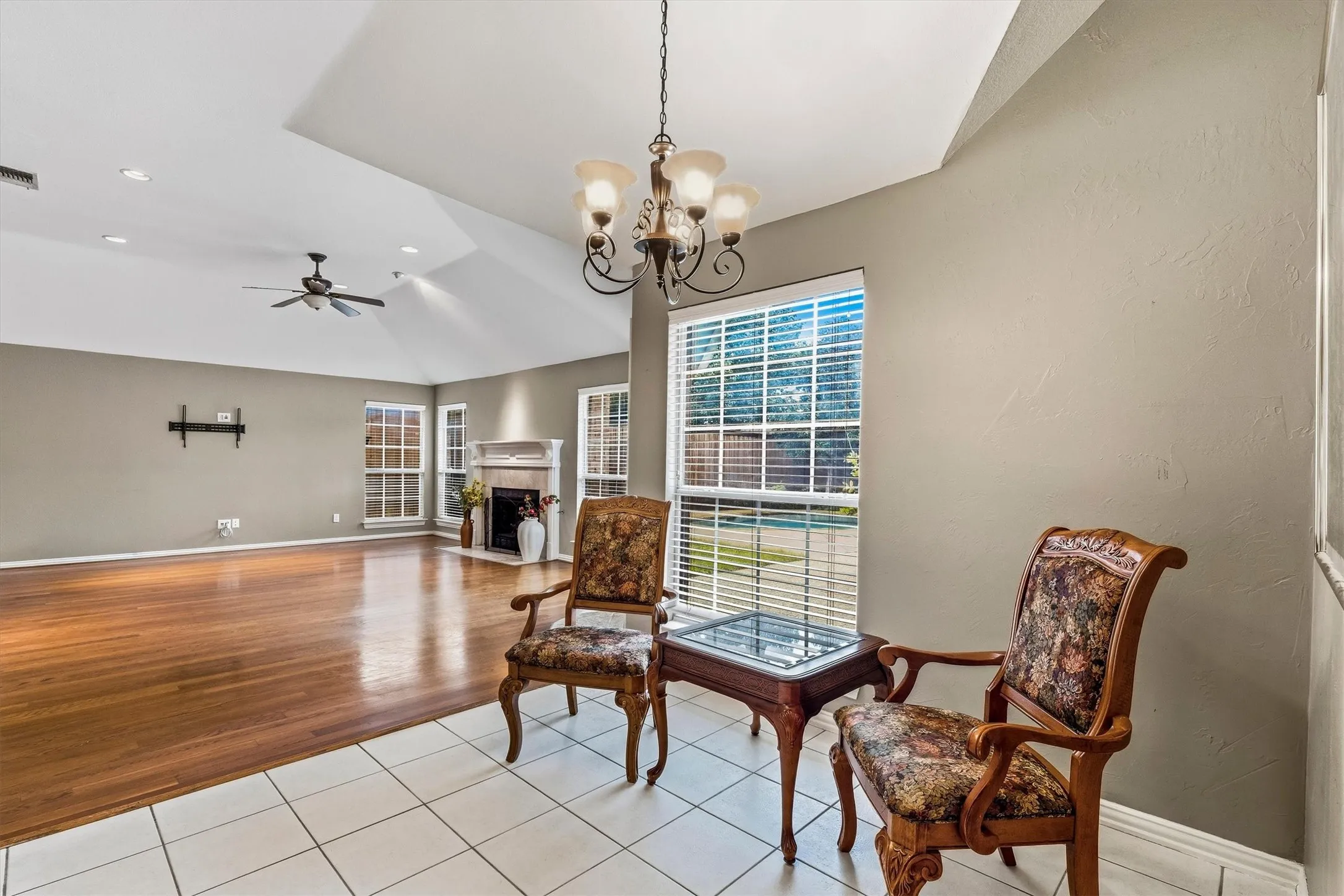 Vaulted ceiling with a ceiling fan, recessed lighting, fireplace with mantel, and wood-finish flooring