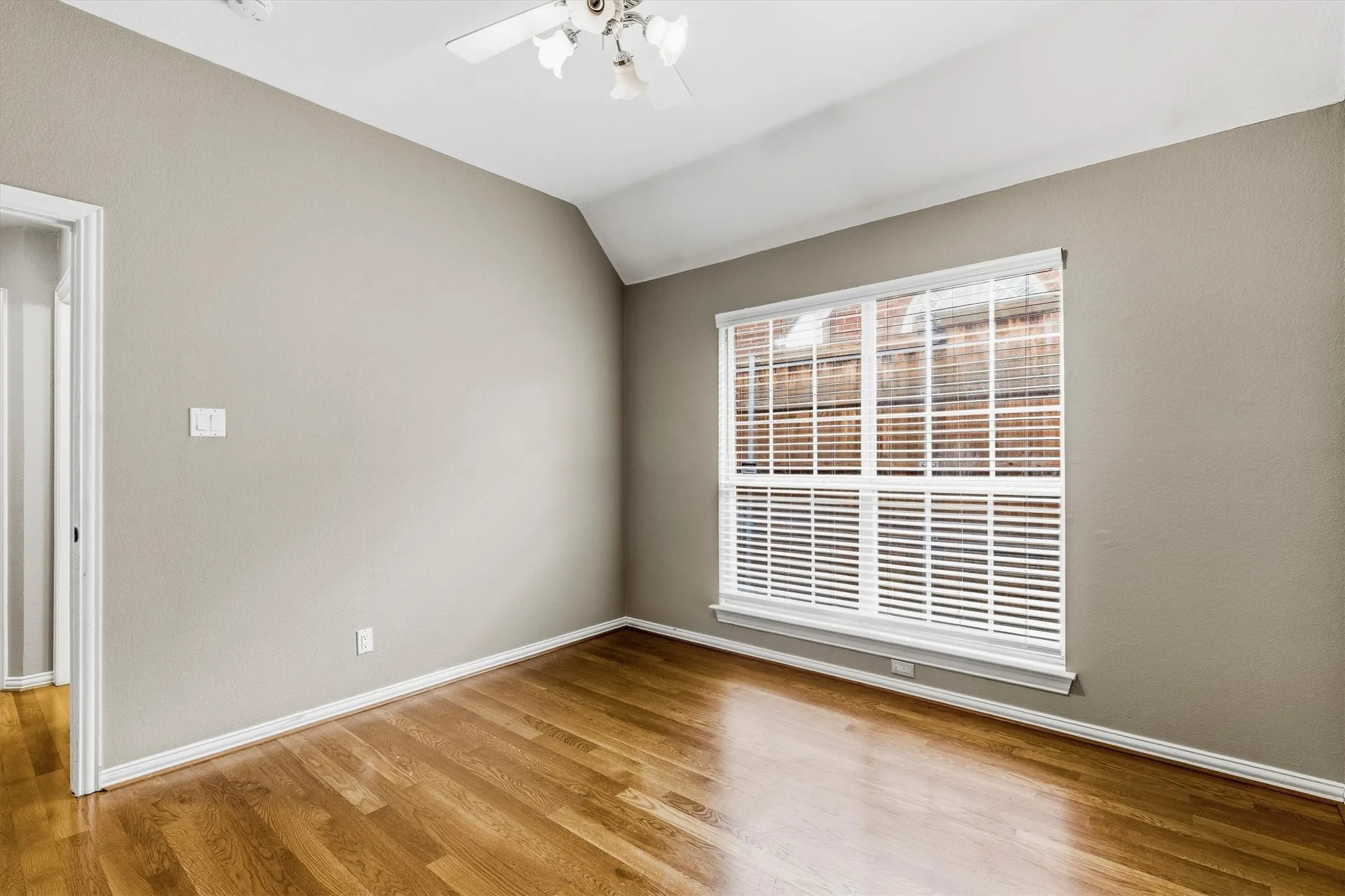 Hardwood-finish flooring, vaulted ceiling, and window with horizontal blinds