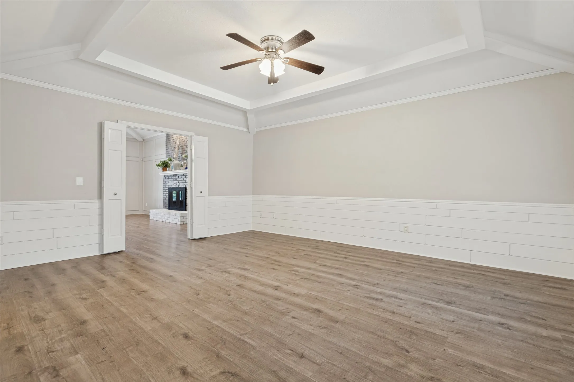 Wood-finish flooring, coffered ceiling, ceiling fan, bi-fold doors, and shiplap wainscoting
