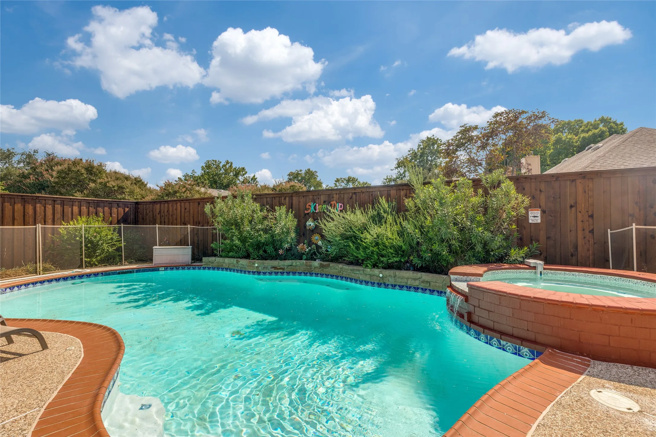 Backyard oasis featuring a swimming pool, integrated hot tub with waterfall, flagstone coping, and a 12' new cedar privacy fence