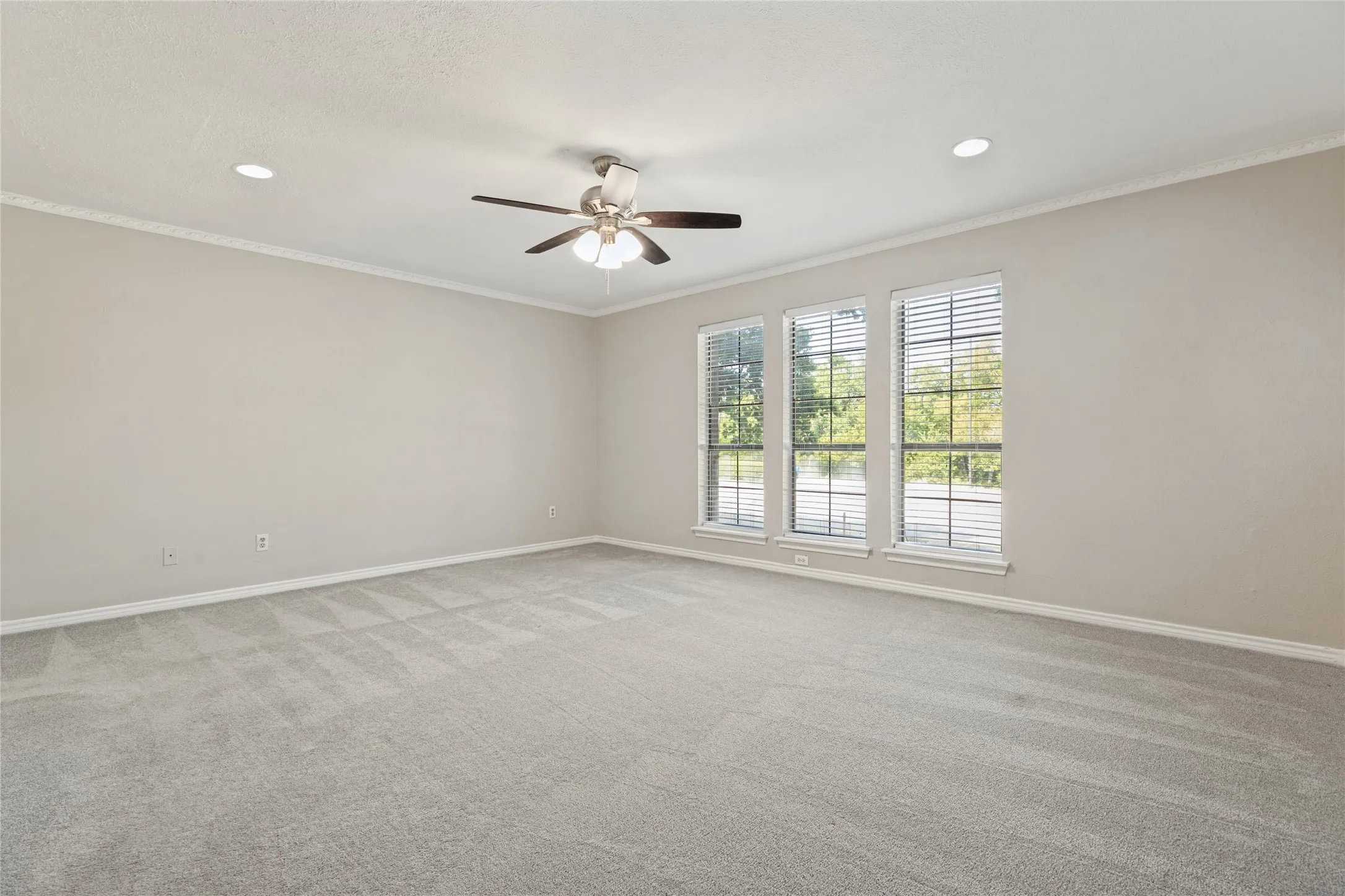Lovely windows in the primary bedroom ,  featuring neutral carpeting, recessed lighting, a ceiling fan, crown molding.