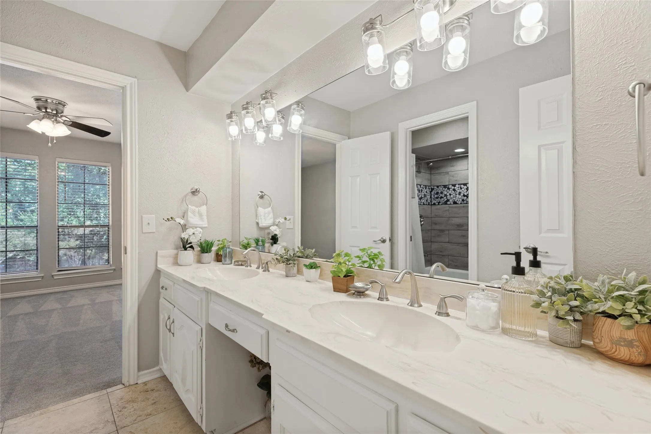Jack & Jill bath with Dual vanity with integrated sinks, brushed nickel fixtures, and a large wall-mounted mirror, separate toilet and bath area