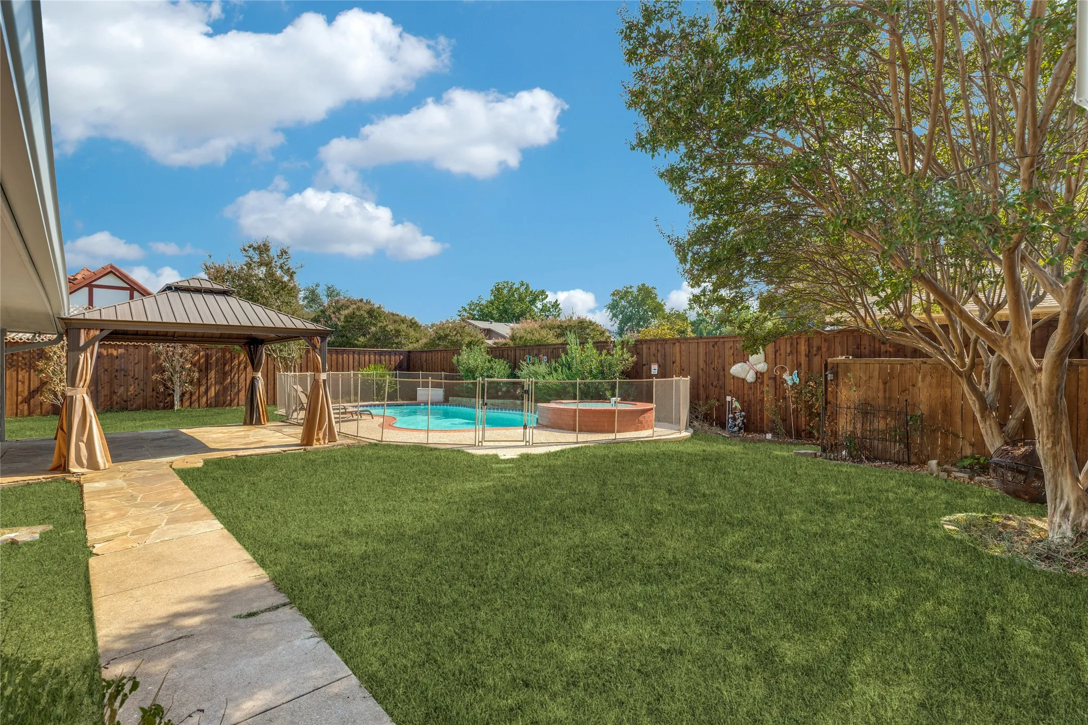 Expansive backyard featuring sidewalk to driveway, large trees and flower beds