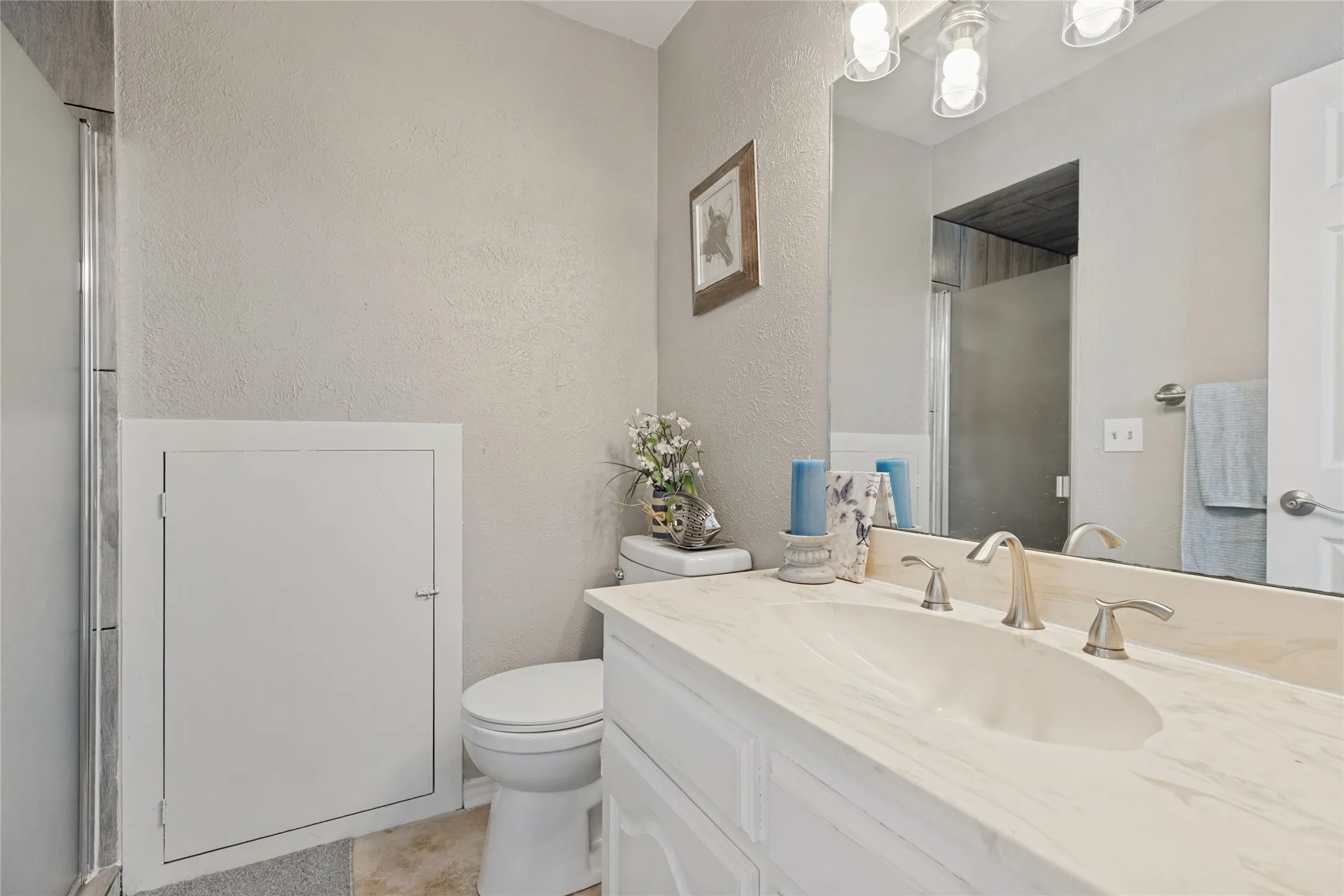 Upstairs ensuite bath, with Vanity with an integrated sink, brushed nickel faucet, and a large mirror, and a walk in shower with custom porcelain tile.