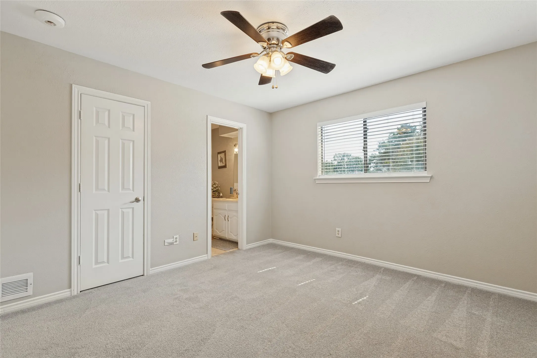 Upstairs second primary bedroom, with ensuite bath, ceiling fan with light fixture, carpeted flooring