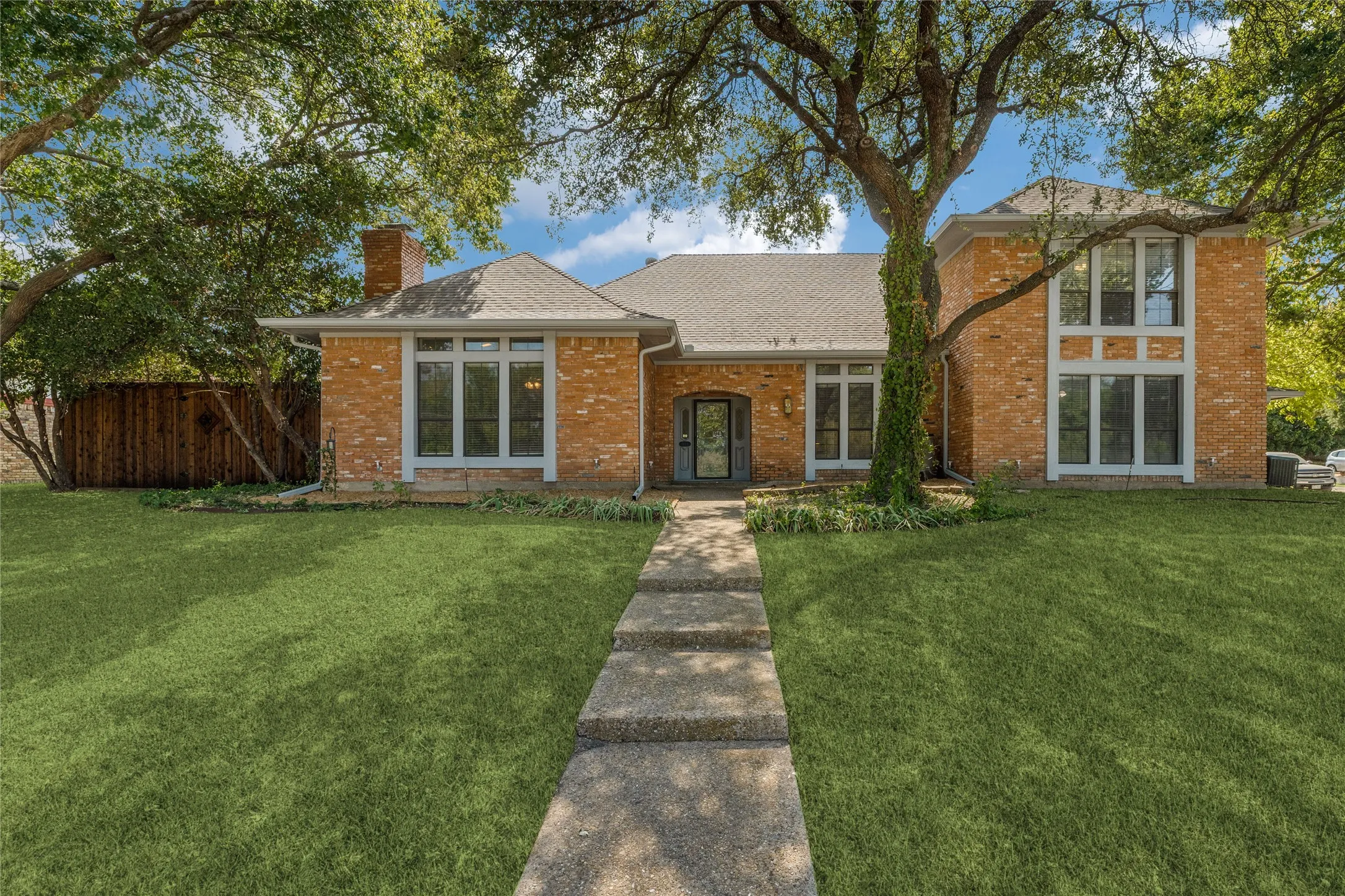 Brick exterior with grey blue matching  trim, multiple large windows, and a prominent front entry.