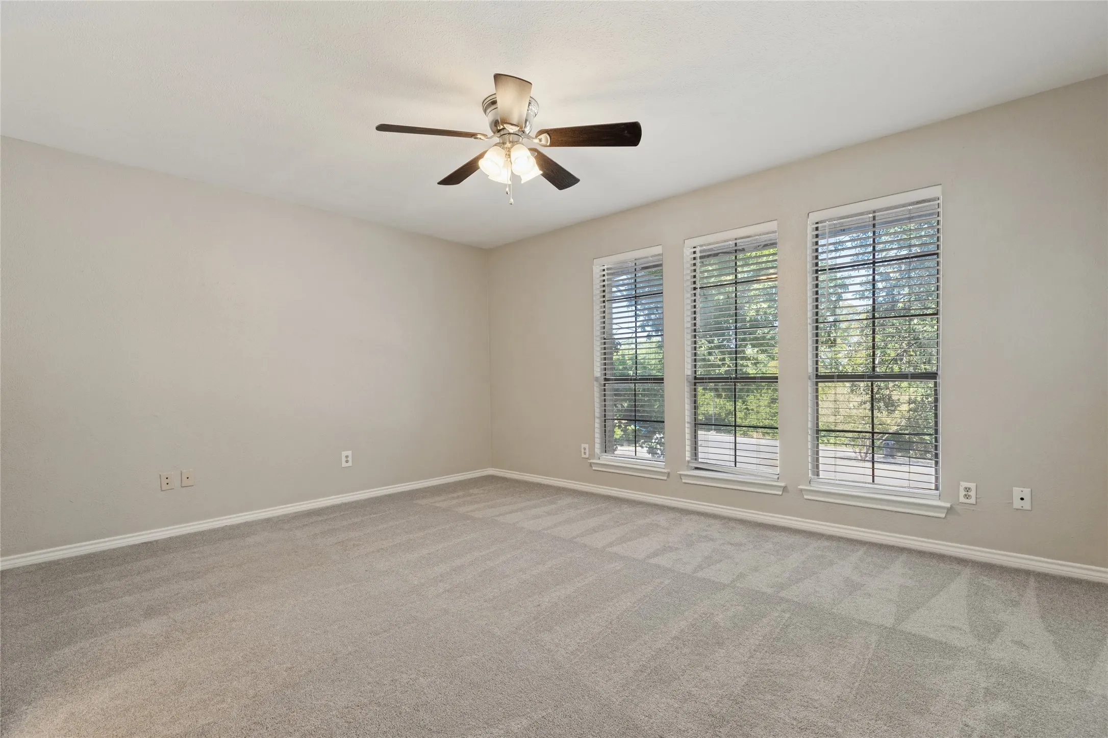 Large upstairs bedroom with the Jack & Jill attached bathroom, has Neutral-toned carpeting, three large windows with blinds, and a ceiling fan with integrated lighting