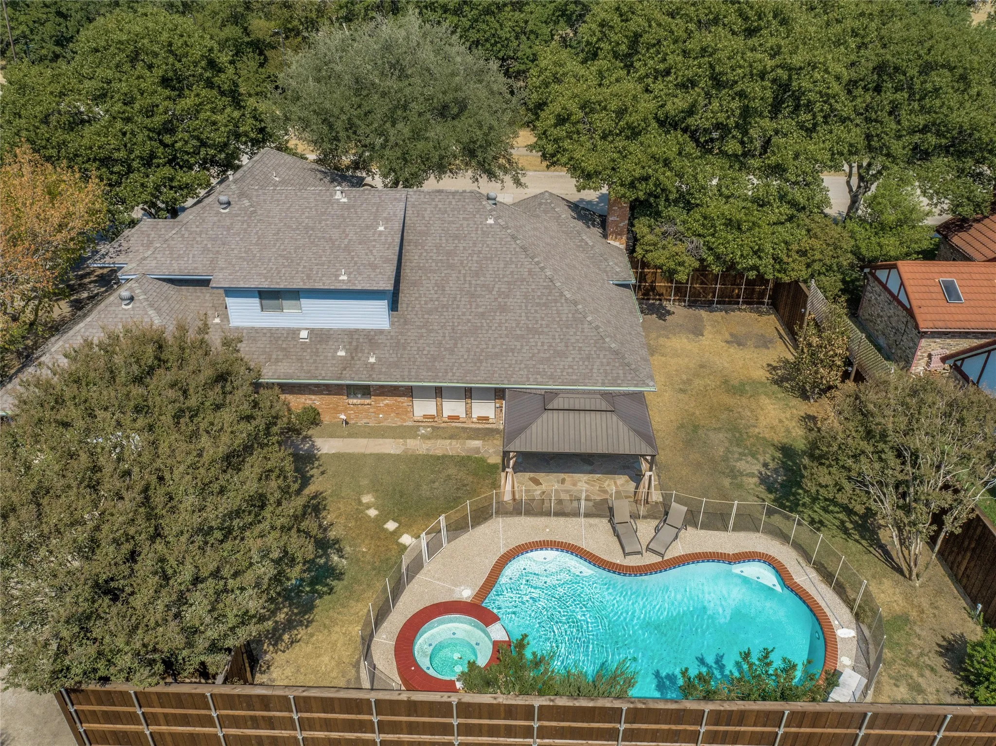 Kidney-shaped swimming pool with an integrated spa, surrounded by a safety fence