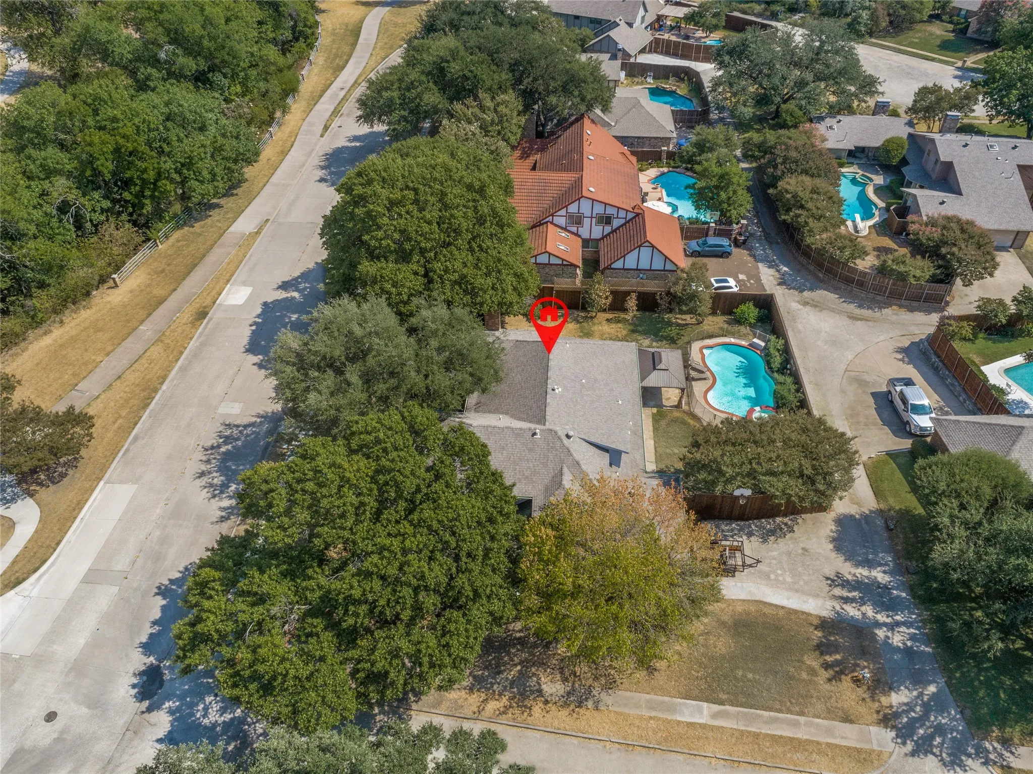 Property with a private pool, mature trees, and a concrete driveway, view of park across the street with expansive walking trail, play areas and creek views