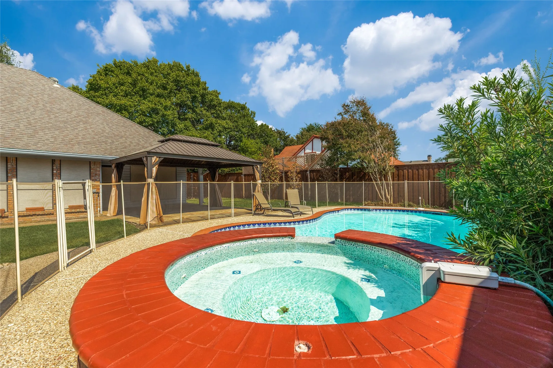 Sparkling integrated spa with a red brick coping, a surrounding safety fence, gorgeous flower bed